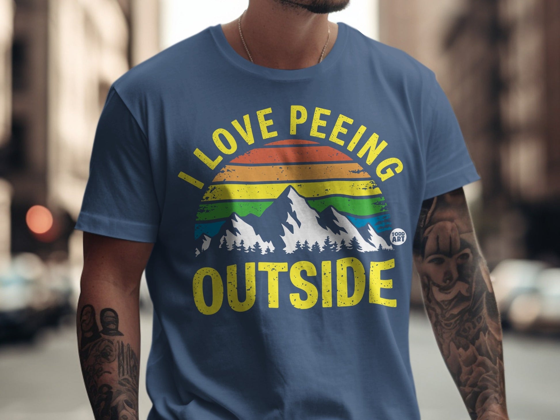 Blue t-shirt with "I LOVE PE*ING OUTSIDE" text and mountain landscape.