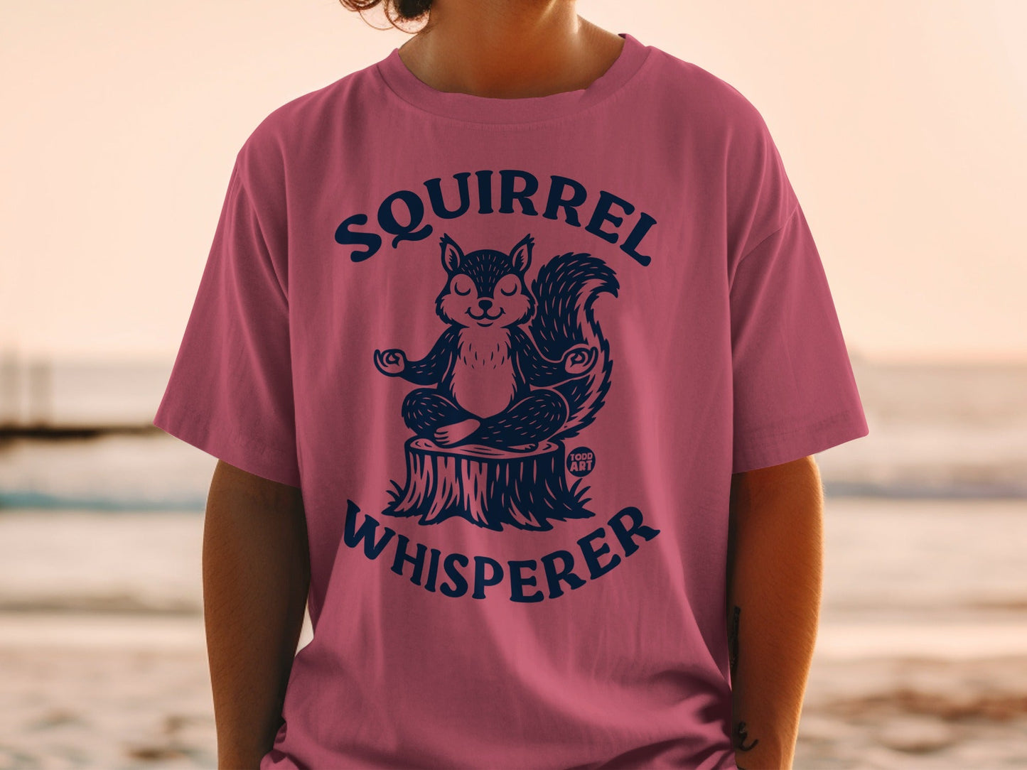 Man wearing pink t-shirt with "Squirrel Whisperer" text and meditating squirrel graphic.