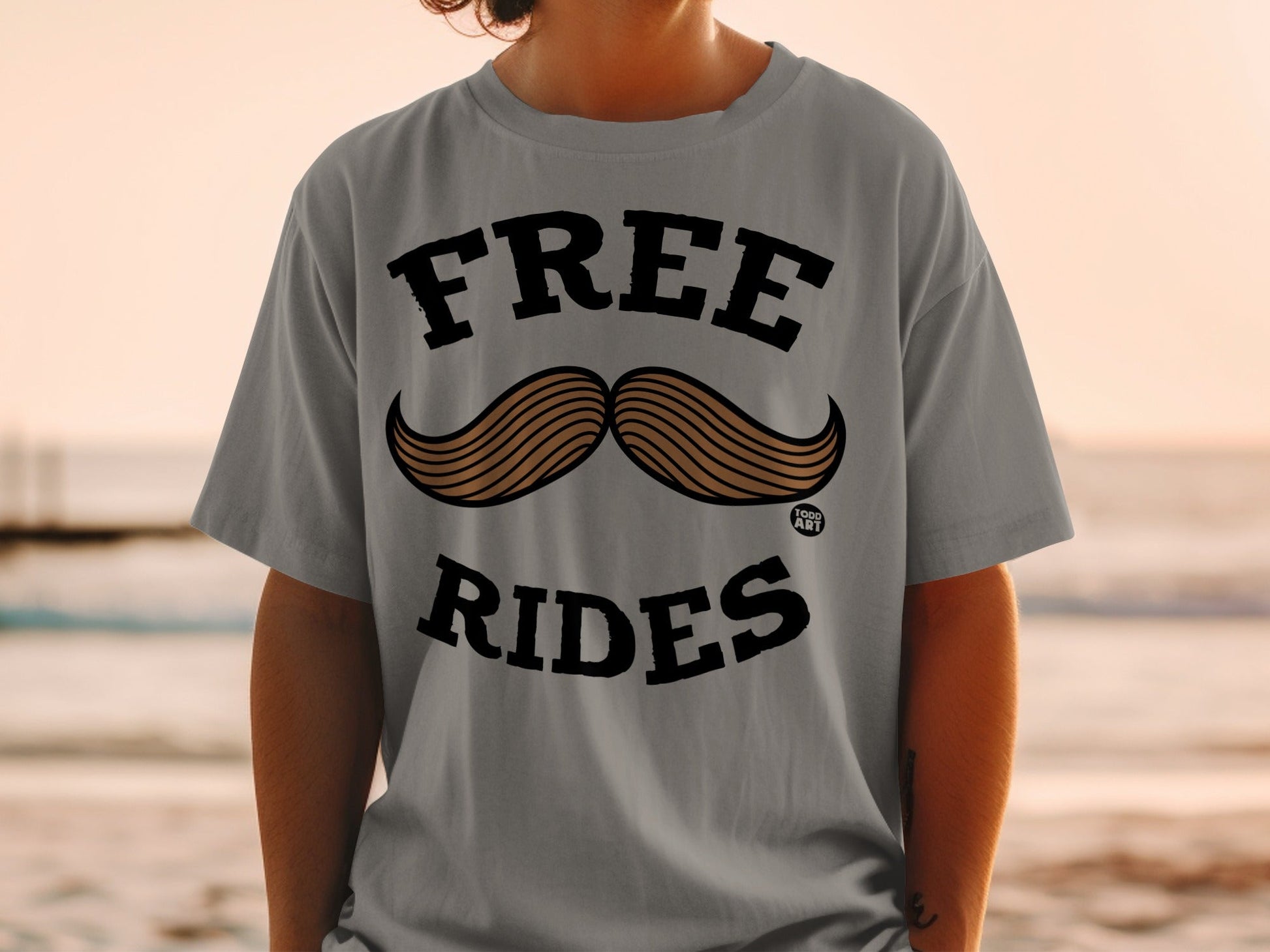 Grey t-shirt with "FREE" above a mustache graphic and "RIDES" below.