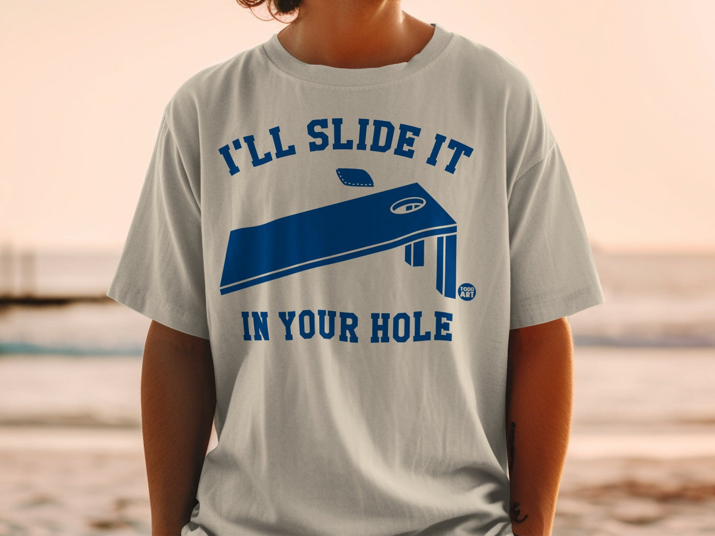 T-shirt with blue cornhole board design and text "I'LL SLIDE IT IN YOUR HOLE".