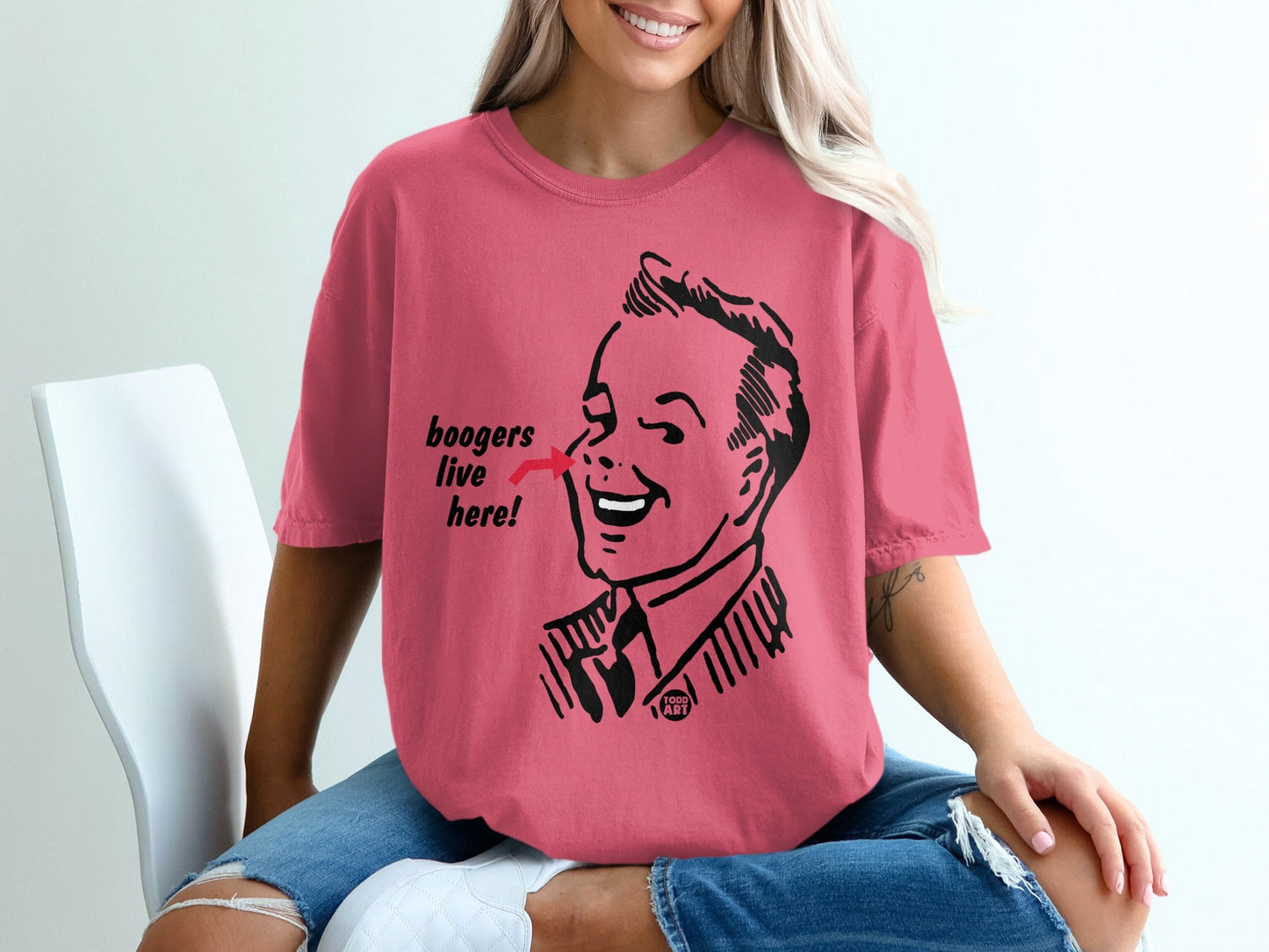 Pink t-shirt with illustration of man's face and text "boogers live here!".