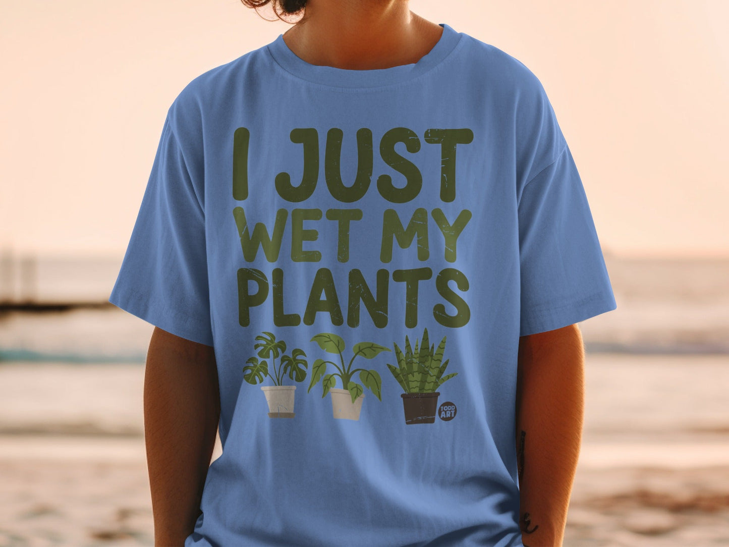 Blue t-shirt with "I JUST WET MY PLANTS" text and three potted plants.