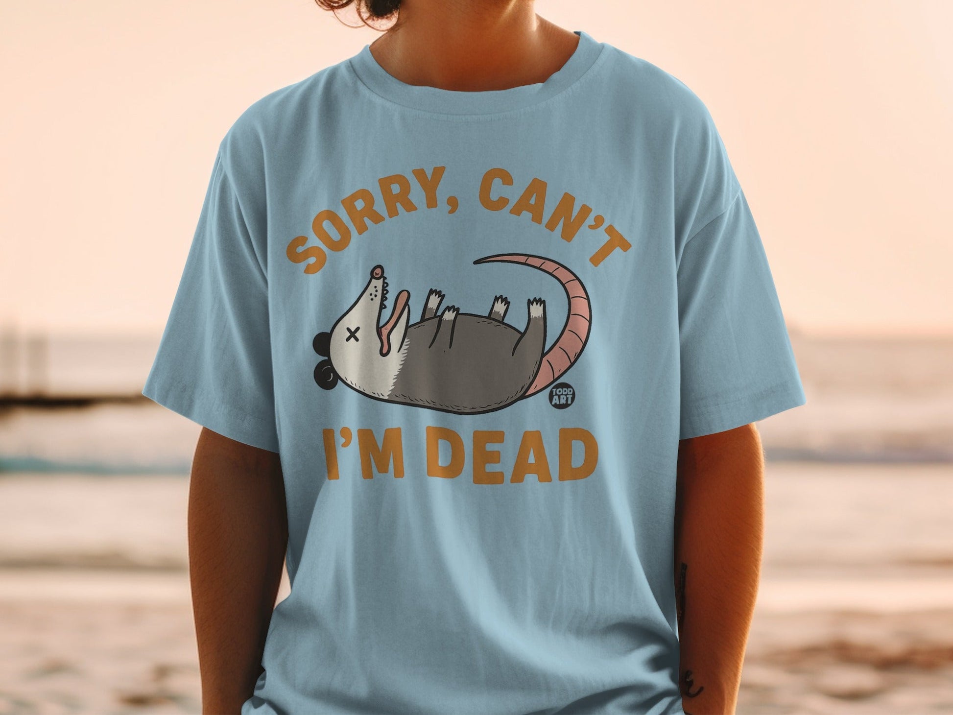 Light blue t-shirt with opossum graphic and text "SORRY, CAN'T I'M DEAD".