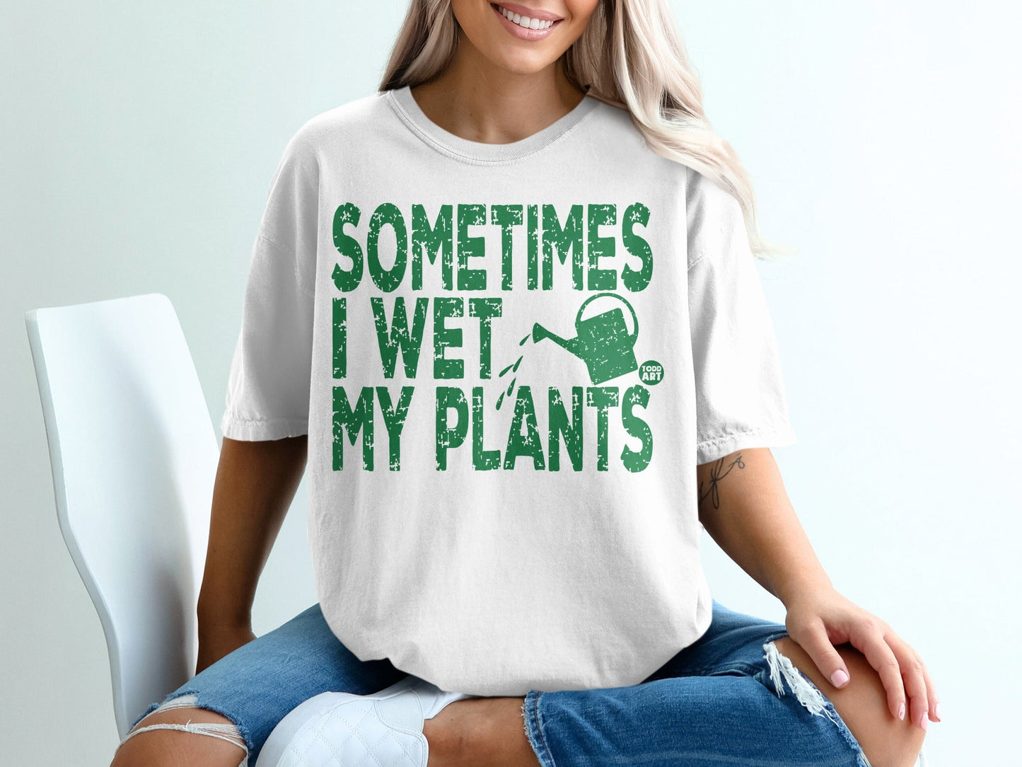 White t-shirt with green text: "Sometimes I Wet My Plants" and a watering can.