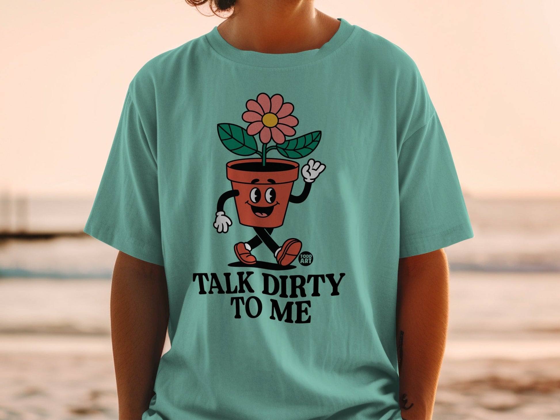 Teal t-shirt featuring a potted plant character with "TALK DIRTY TO ME" text.