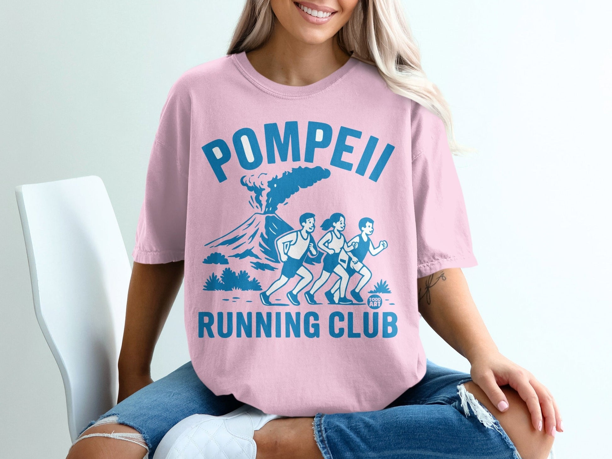 Pink t-shirt with Pompeii Running Club graphic featuring volcano and runners.