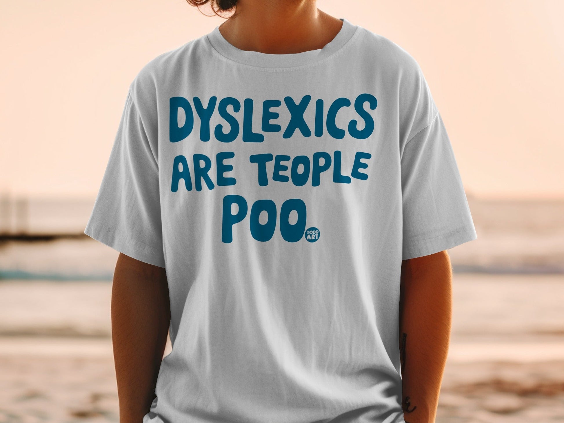 White t-shirt with blue text "DYSLEXICS ARE TEOPLe POO".