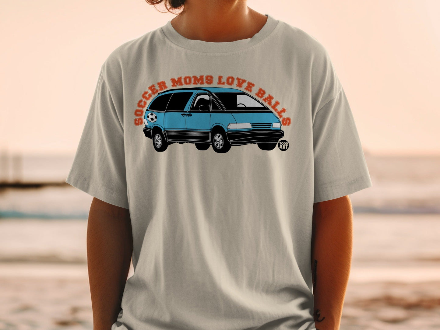 T-shirt with graphic of blue minivan and text "Soccer Moms Love Balls".