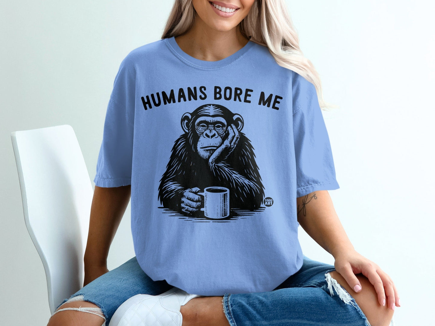 Light blue t-shirt with black text "HUMANS BORE ME" and a chimpanzee holding a mug.