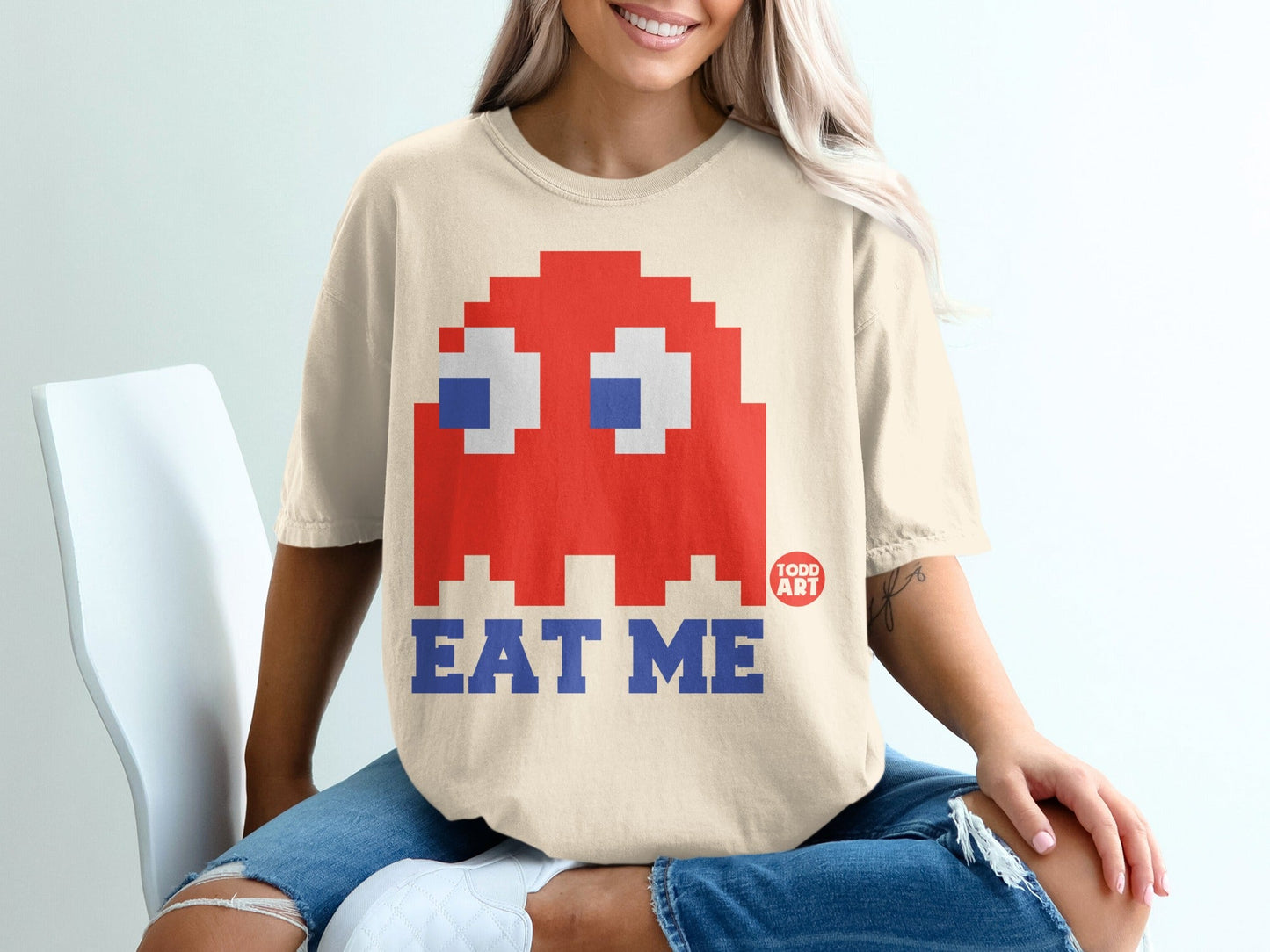 Cream t-shirt with pixelated red Pac-Man ghost and "EAT ME" text.