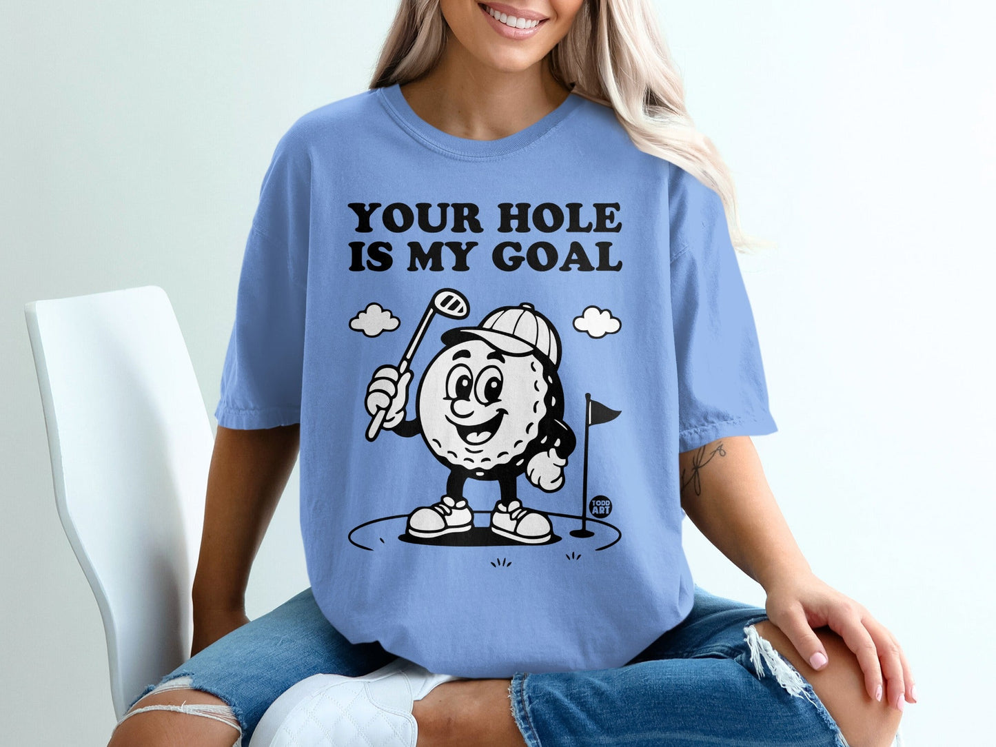 T-shirt graphic with cartoon golf ball, flag, and text "YOUR HOLE IS MY GOAL".