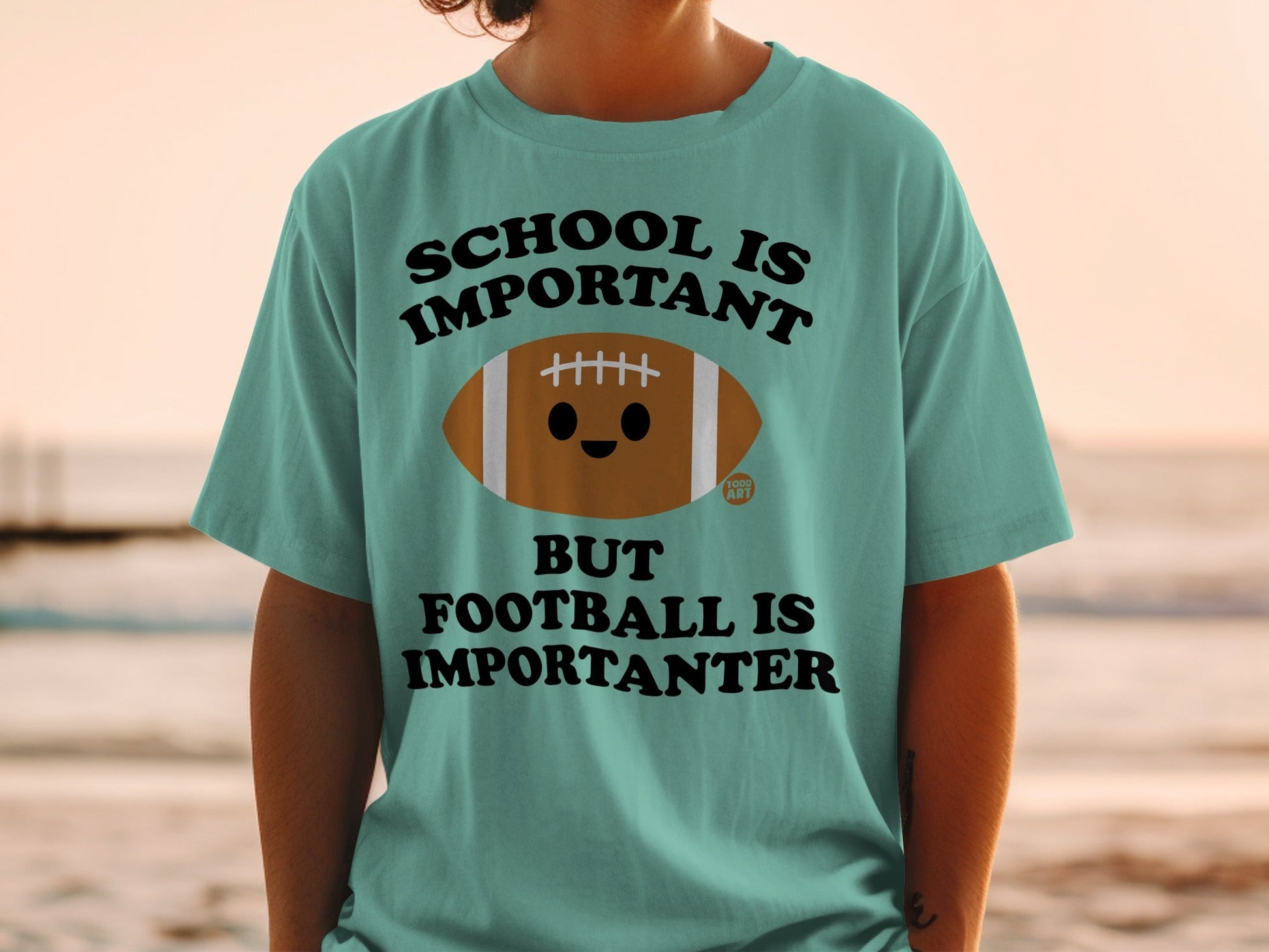 Teal t-shirt with "School is important but football is importanter" and a cartoon football.