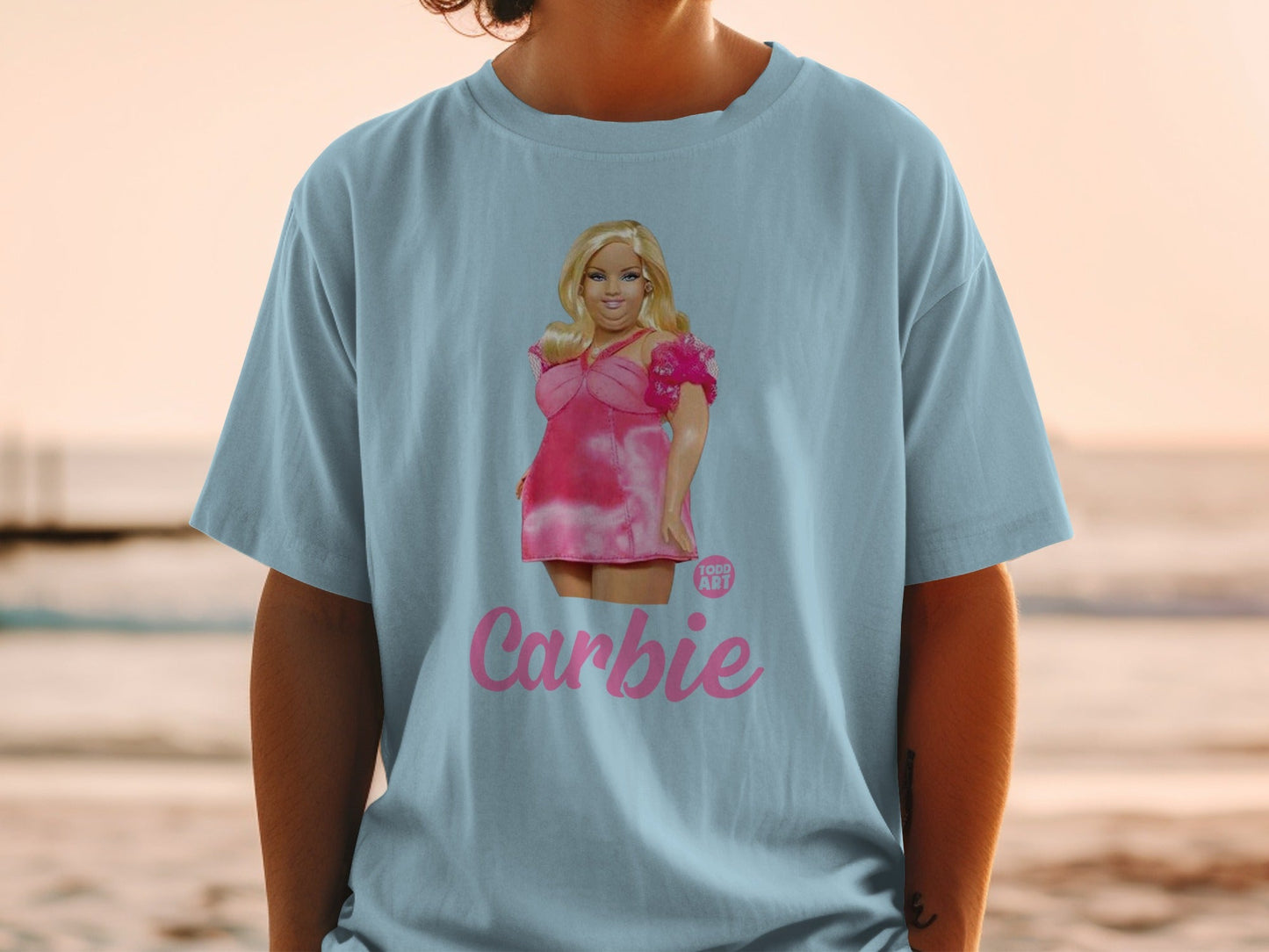 Woman wearing a light blue t-shirt with a pink Barbie graphic and text.