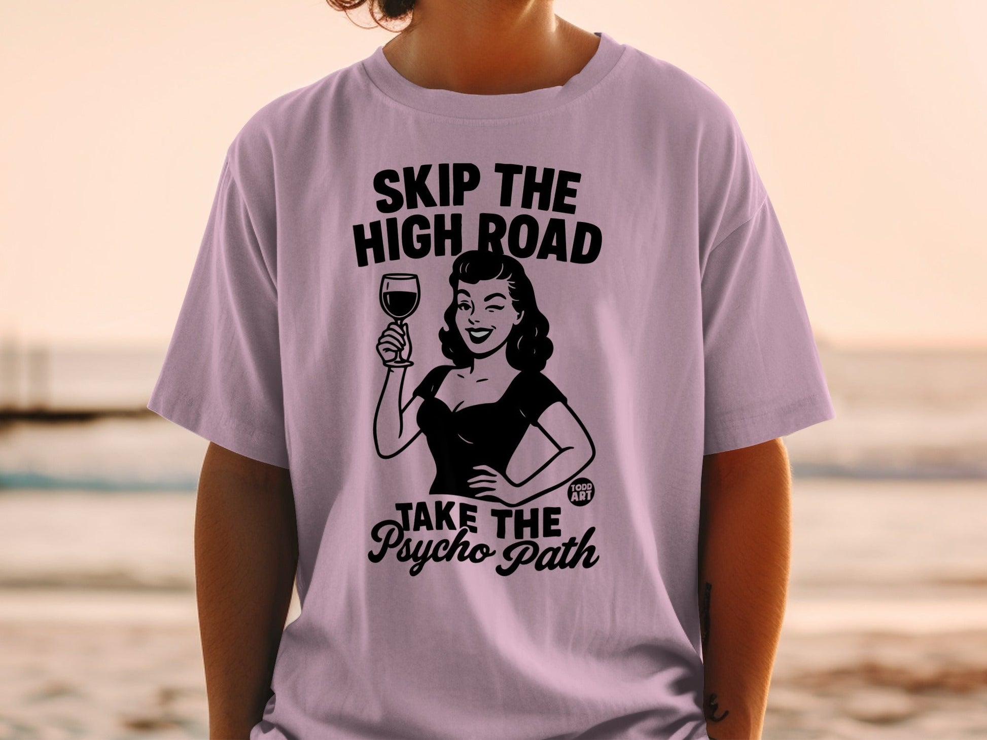 Woman in lilac t-shirt with "Skip The High Road Take The Psycho Path" text and graphic.