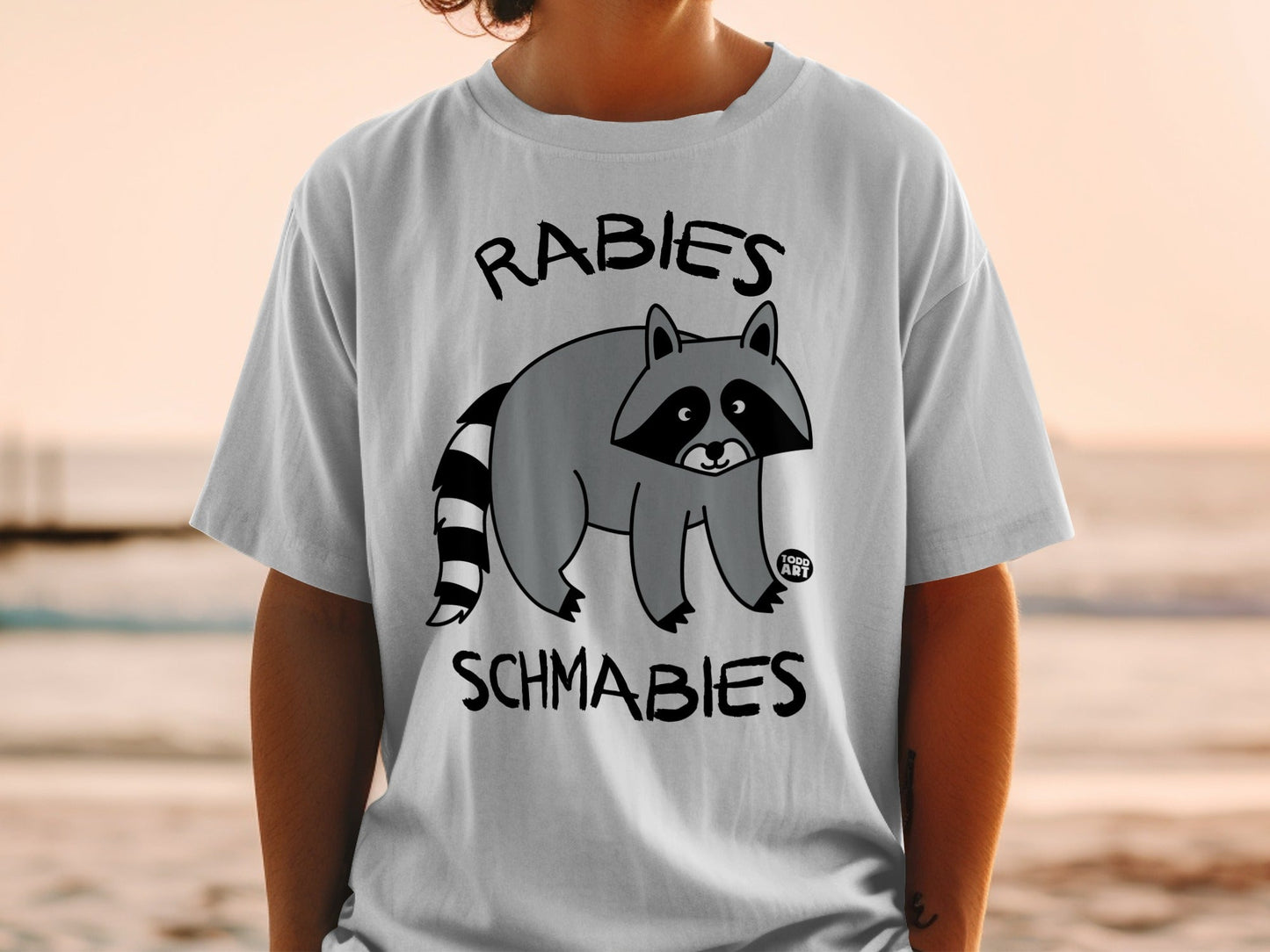 T-shirt with cartoon raccoon and text "Rabies Schmabies".