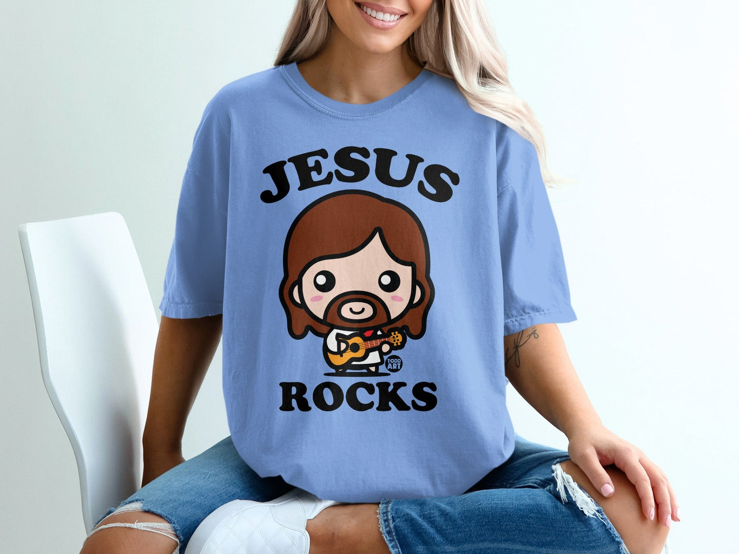 Chibi Jesus playing guitar on a blue t-shirt.