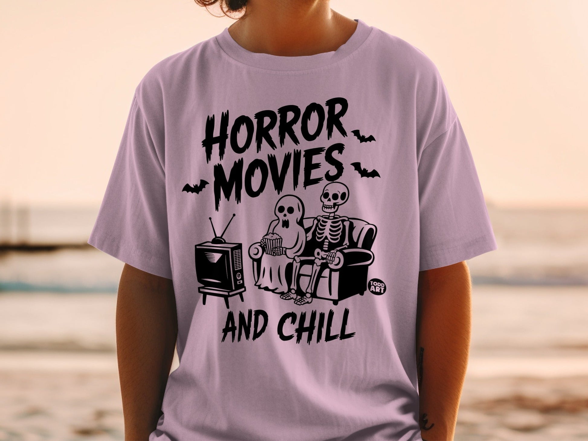 Lavender t-shirt with "HORROR MOVIES AND CHILL" and skeleton couple watching TV.