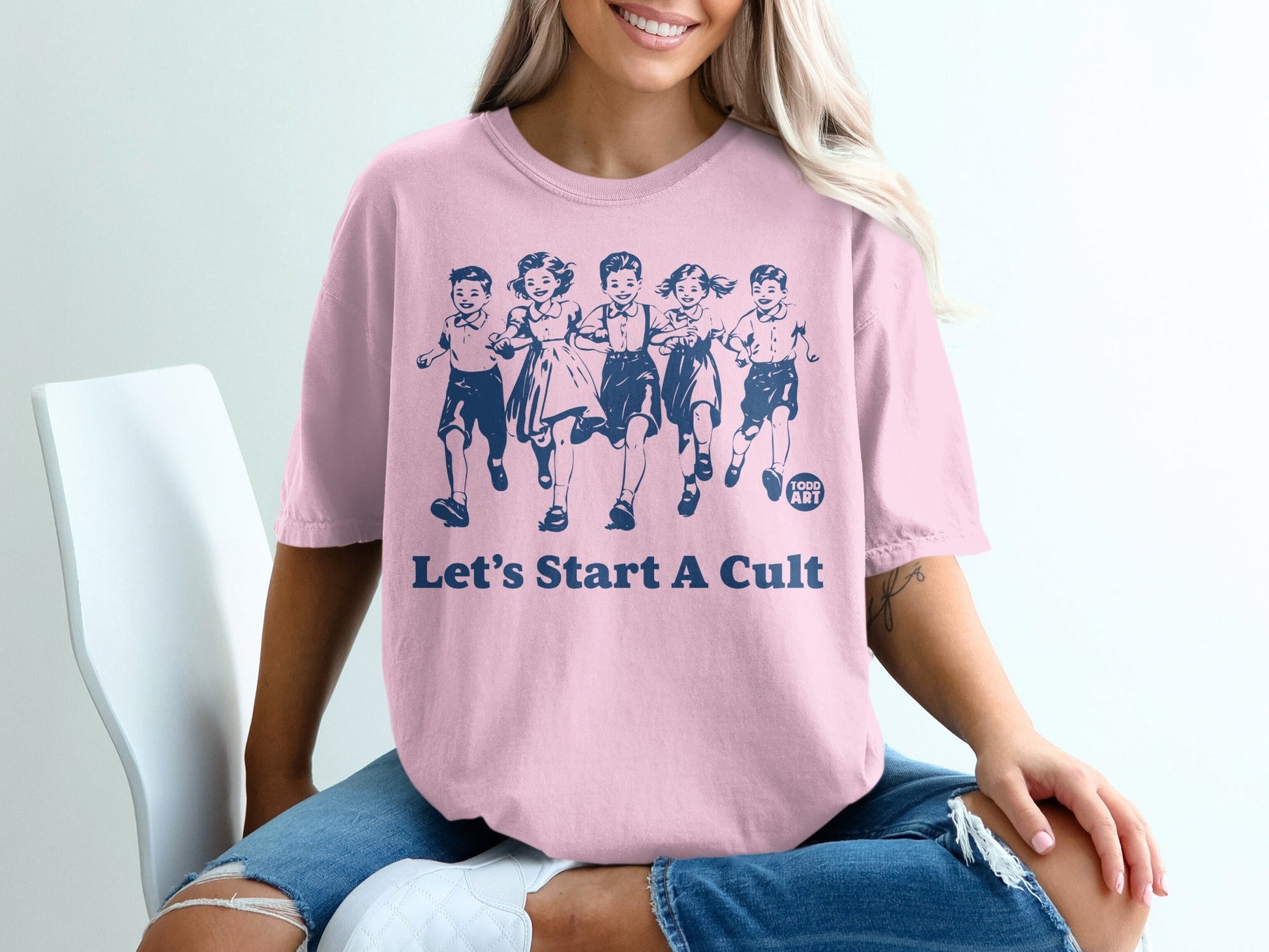 Pink t-shirt with children running and "Let's Start A Cult" text.