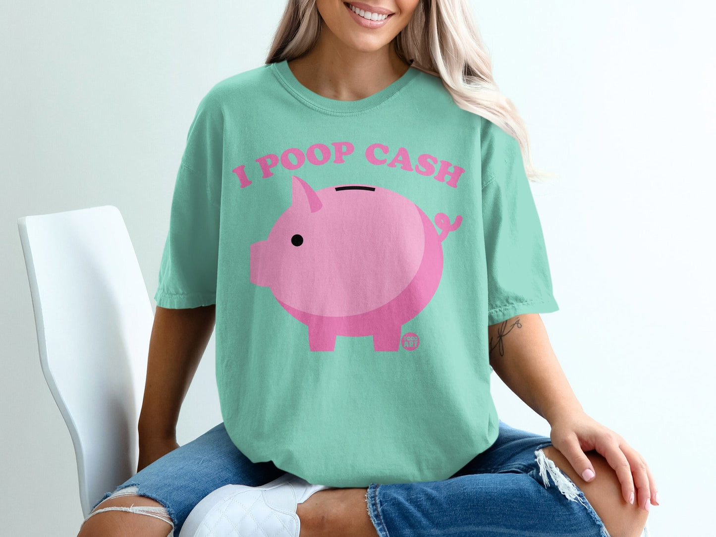 Piggy bank graphic and text "I POOP CASH" on a mint green t-shirt.