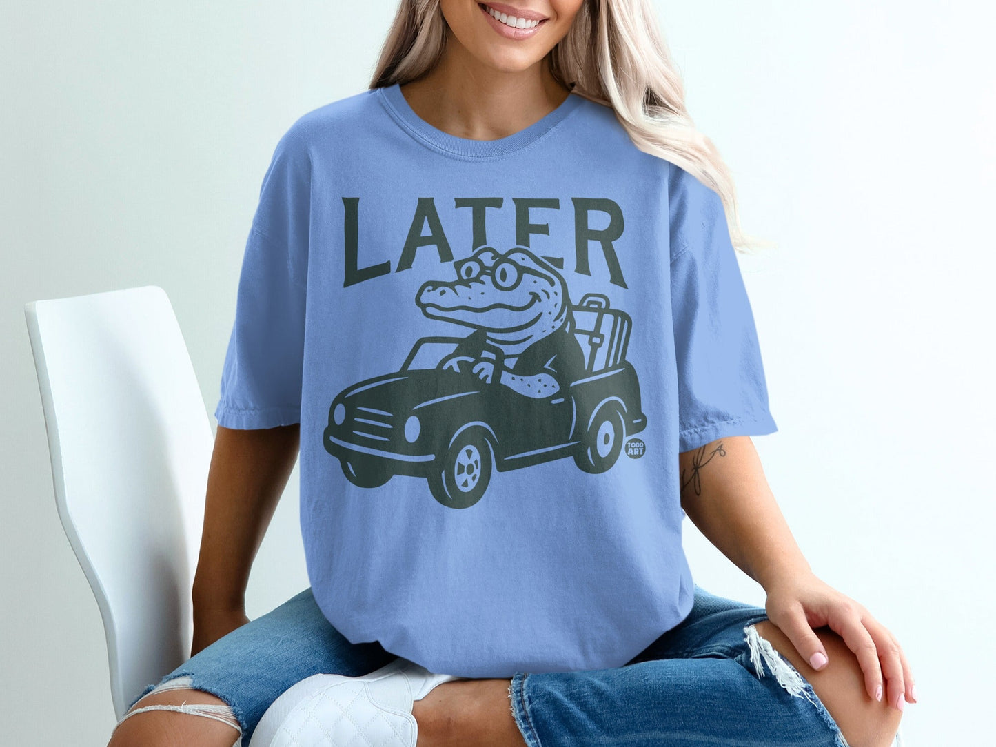 Blue t-shirt with a cartoon alligator driving a car and the word "LATER".