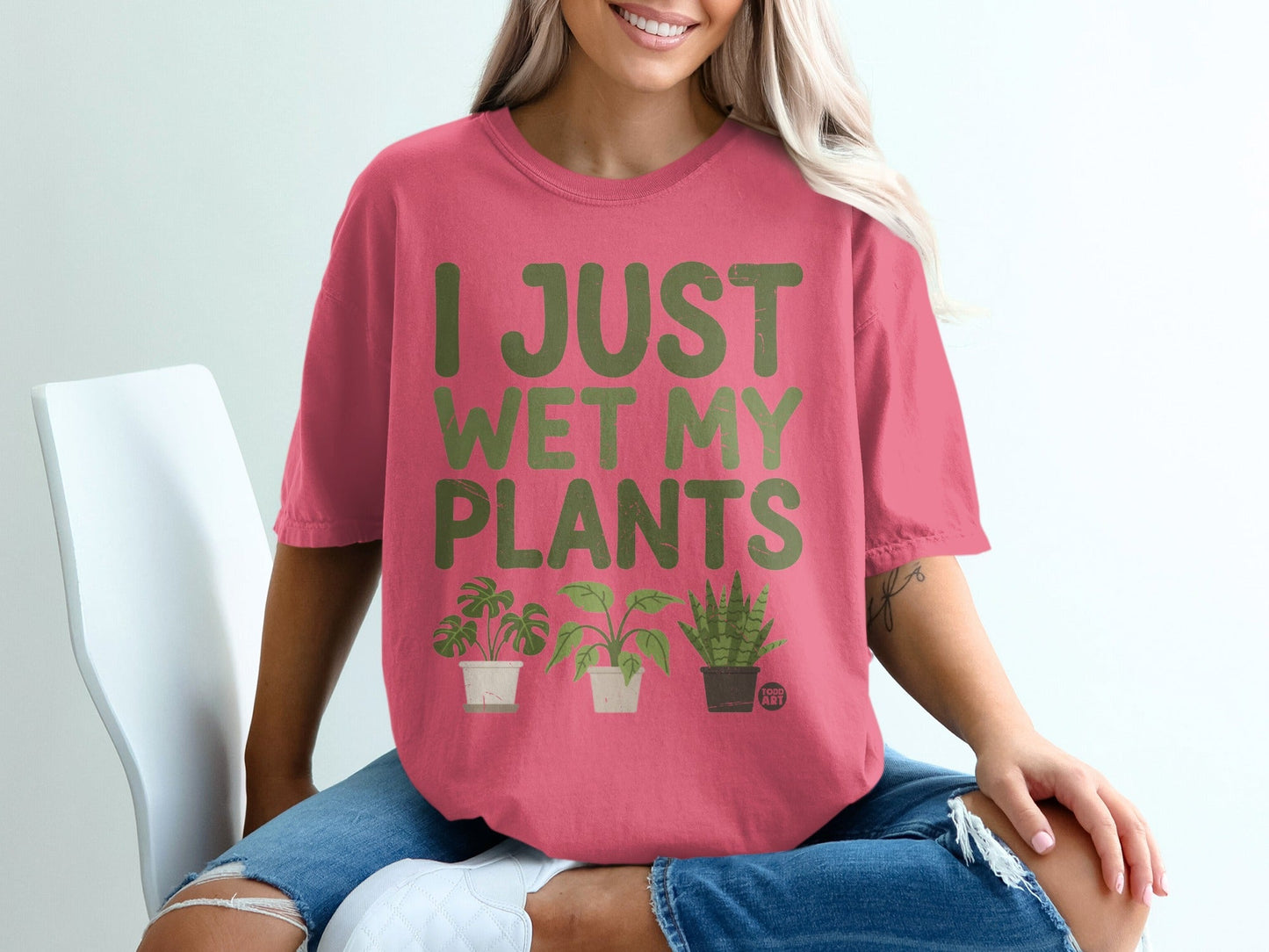 Pink t-shirt with green text "I JUST WET MY PLANTS" and three potted plants.