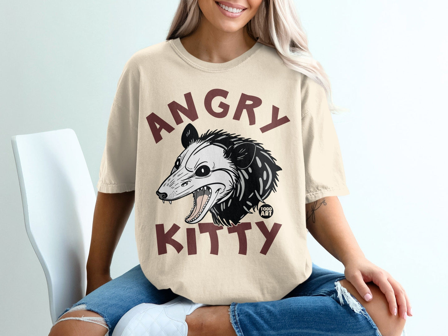 Tan t-shirt with a black and white opossum and text "ANGRY KITTY".