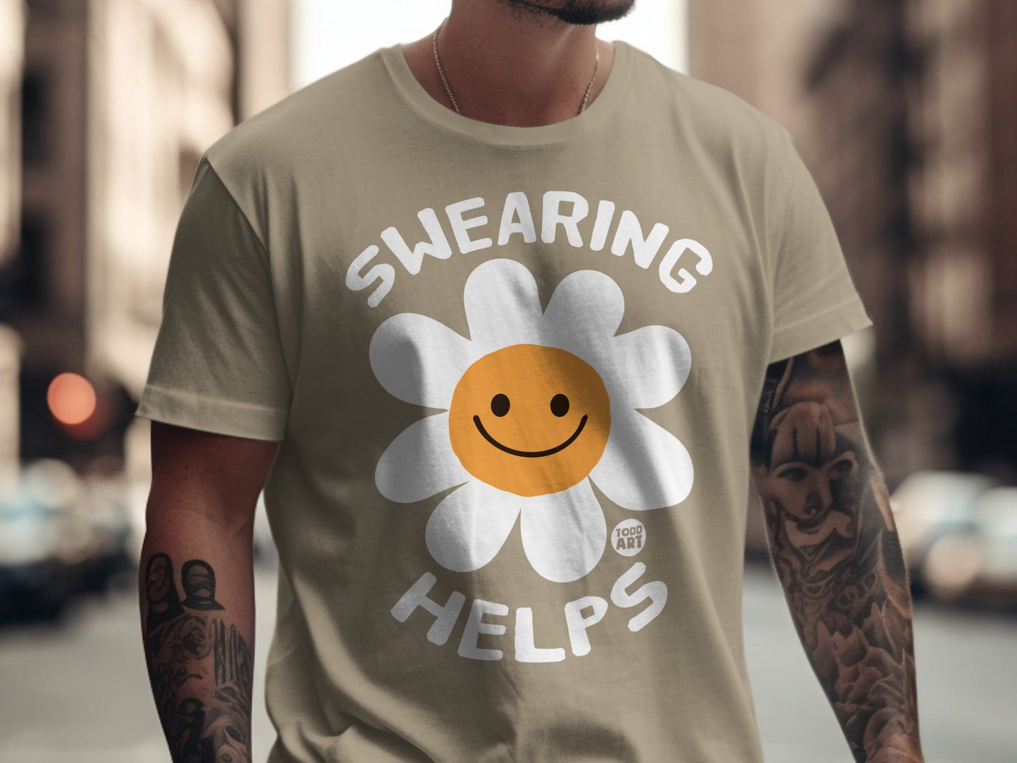 Tan t-shirt with white daisy graphic and "SWEARING HELPS" text.