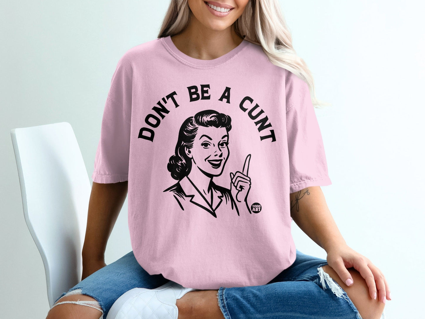 Pink t-shirt with black text "DON'T BE A CUNT" and retro woman graphic.