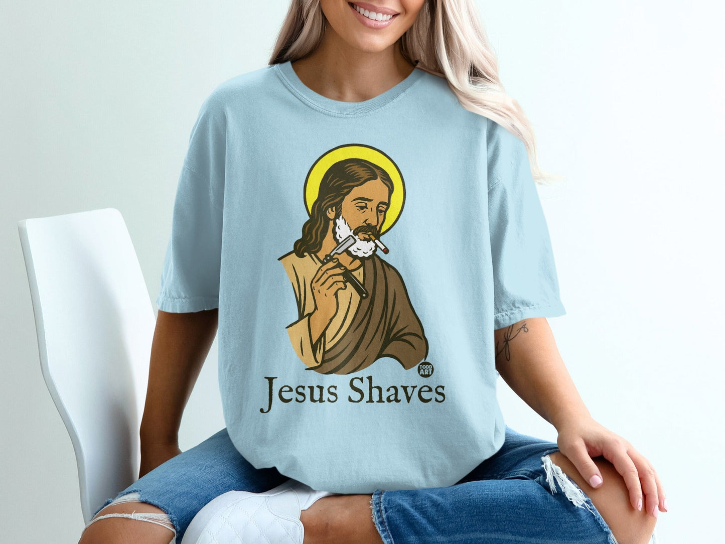 Light blue t-shirt with cartoon of Jesus shaving with a razor.