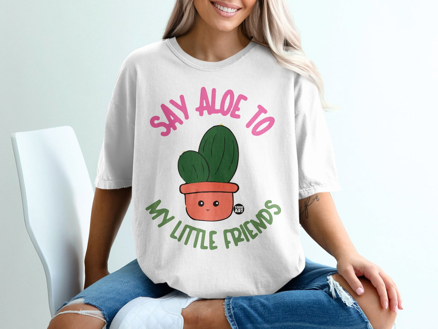 White t-shirt with "Say aloe to my little friends" text and smiling potted cactus.