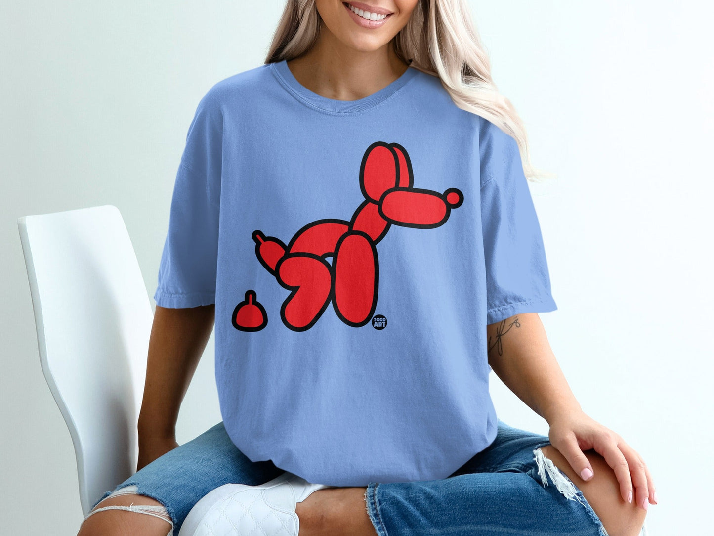 Blue t-shirt with a red balloon dog and a small red object.