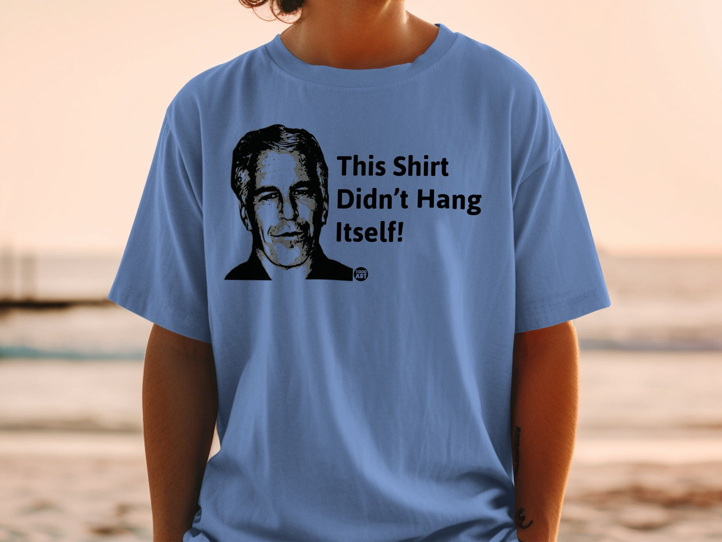 Blue t-shirt with black graphic of a man's head and text: "This Shirt Didn't Hang Itself!"