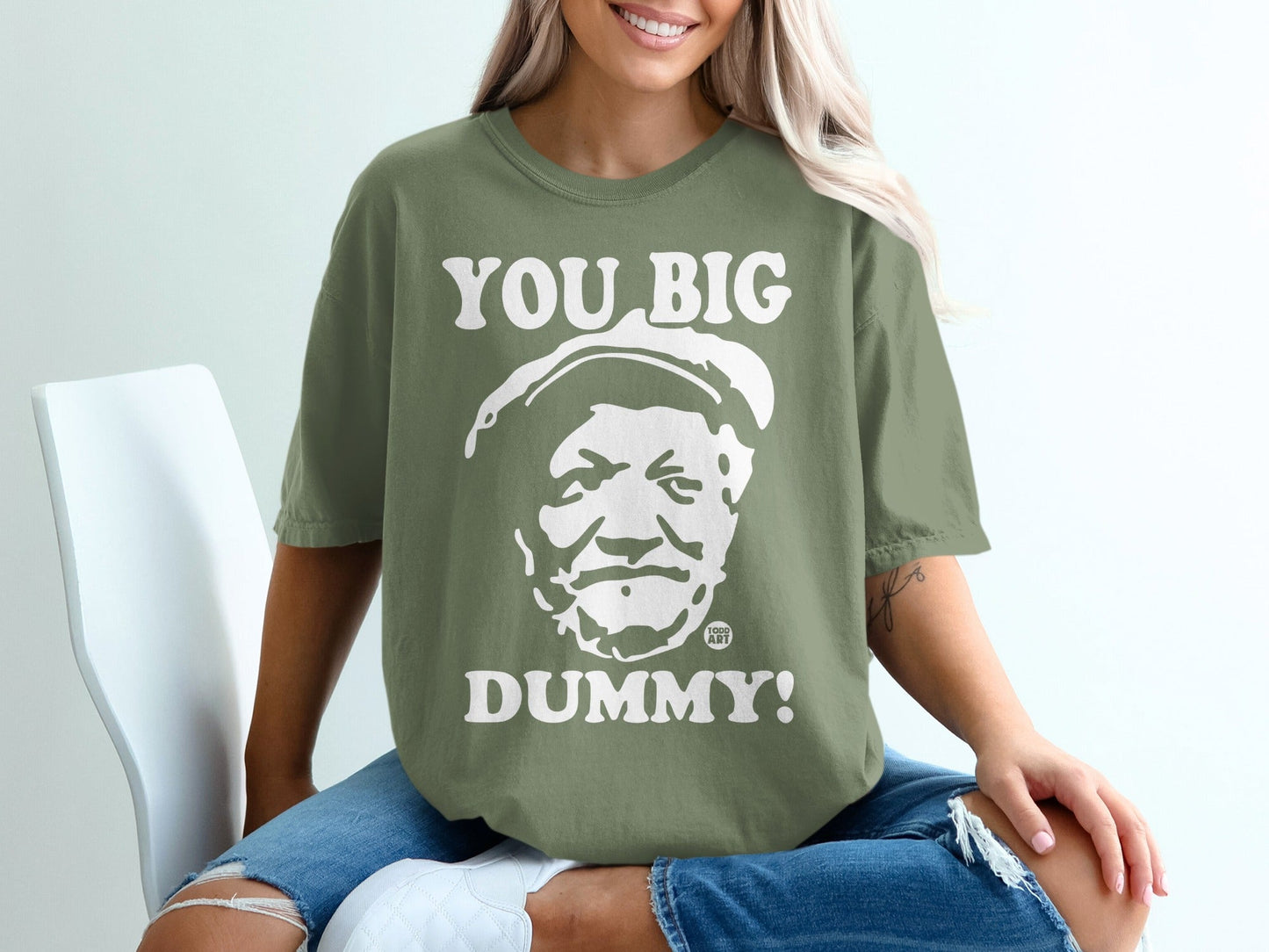 Green t-shirt with "YOU BIG DUMMY!" and a cartoon face printed on it.