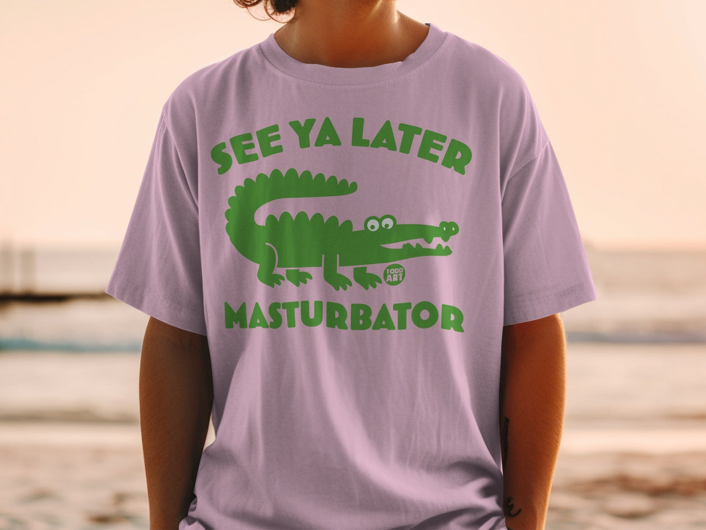 Green alligator graphic with "SEE YA LATER" and "TODD ART" text on a lavender t-shirt.