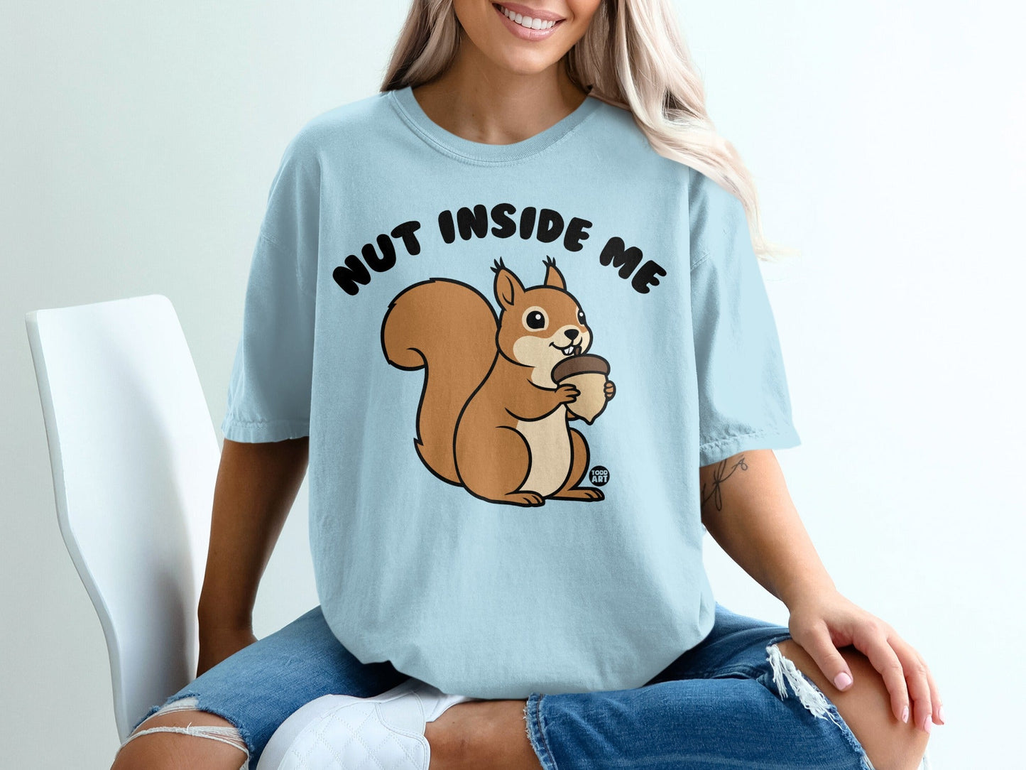 Light blue t-shirt with a cartoon squirrel holding an acorn and the text "NUT INSIDE ME".