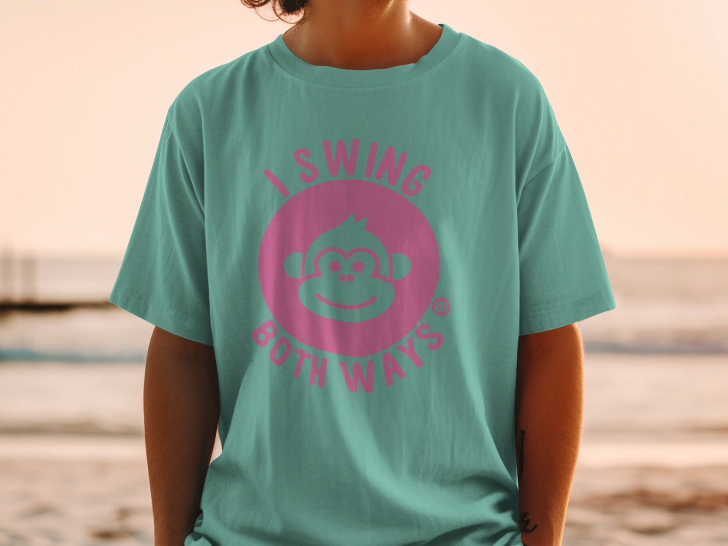 Teal t-shirt with a pink monkey face and text "I SWING BOTH WAYS".