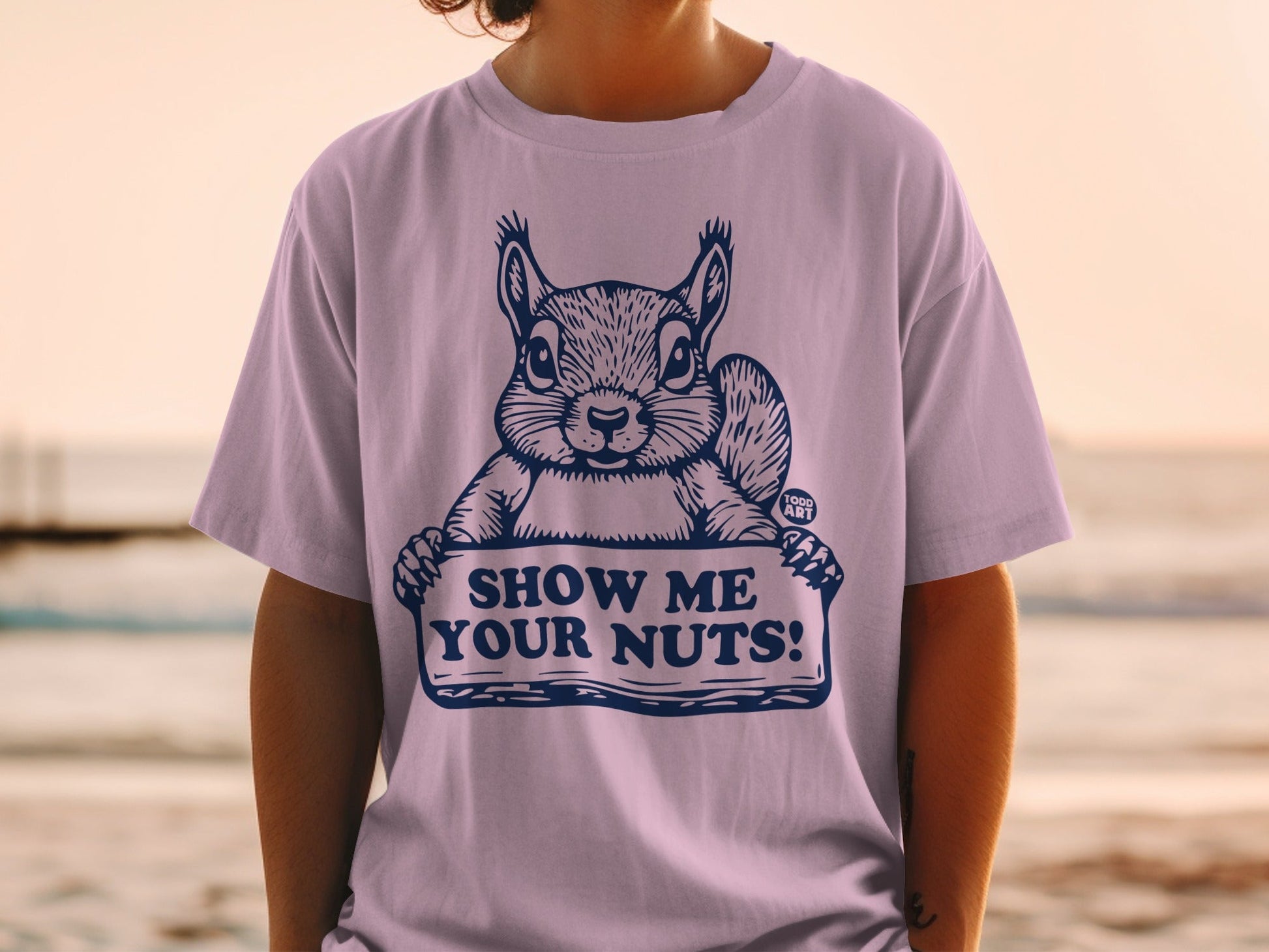 T-shirt with a squirrel holding a sign that says "SHOW ME YOUR NUTS!".