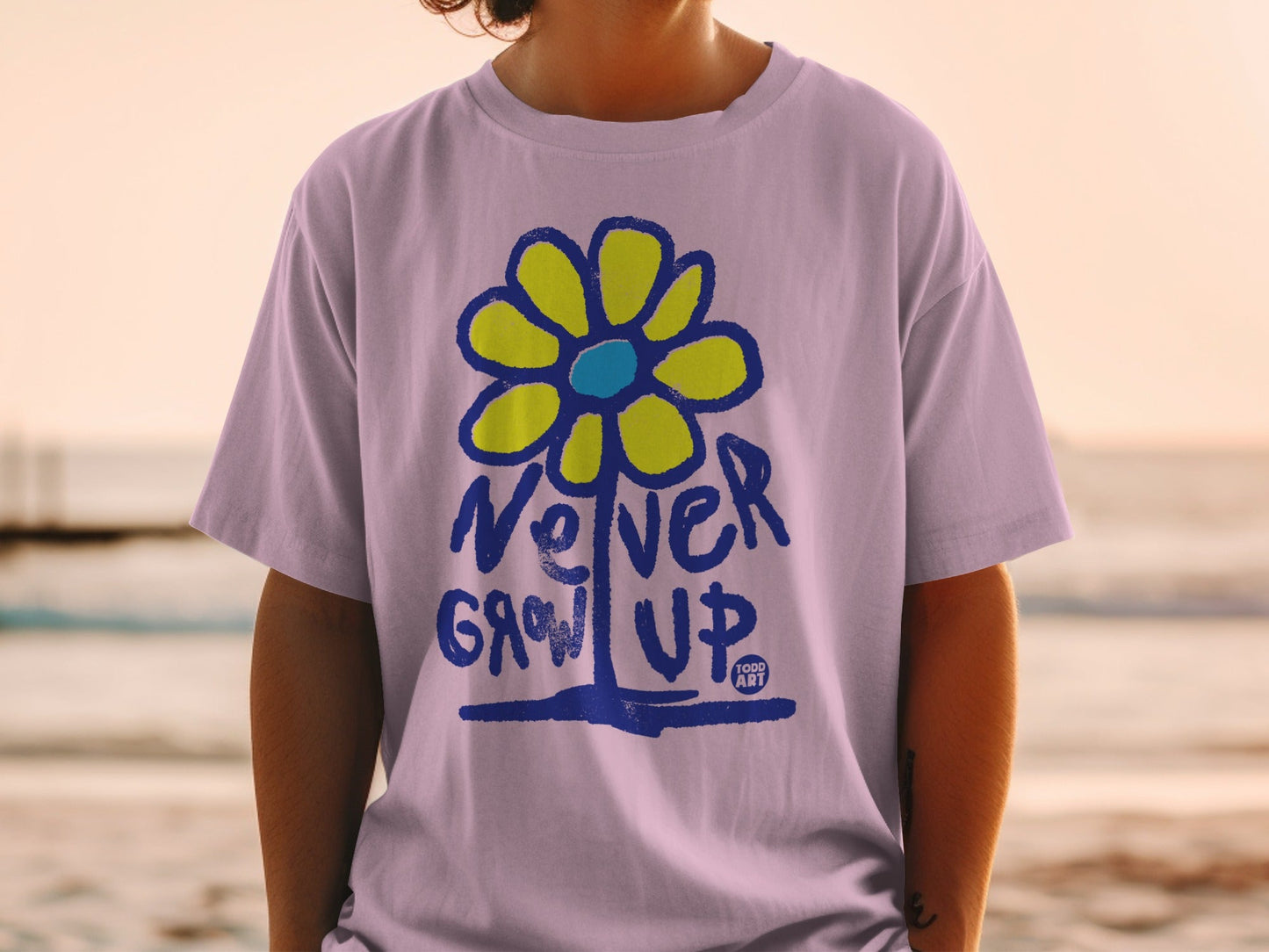 Purple t-shirt with blue and yellow flower graphic and "Never Grow Up" text.