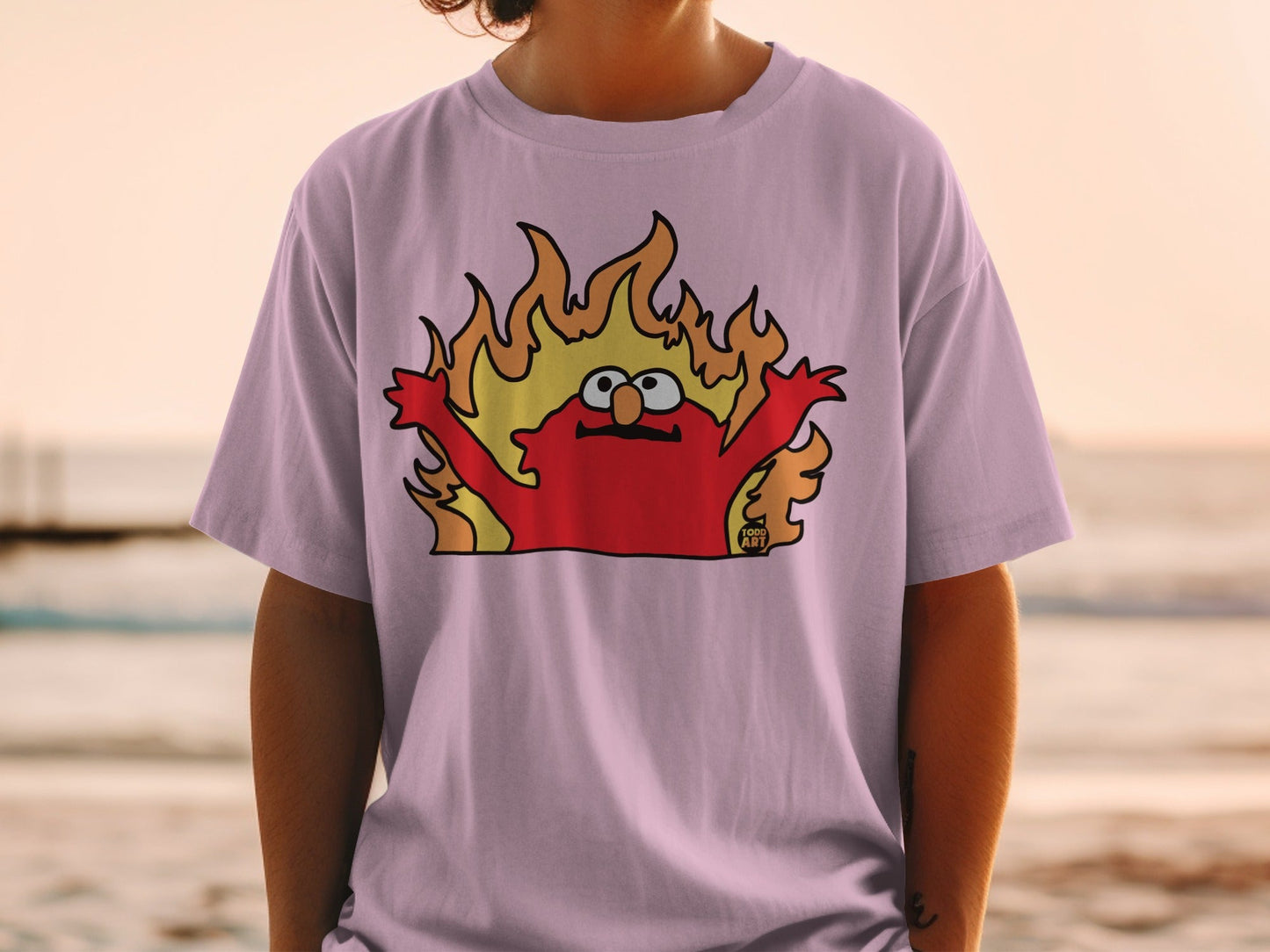 Elmo character in flames graphic on a light purple t-shirt.