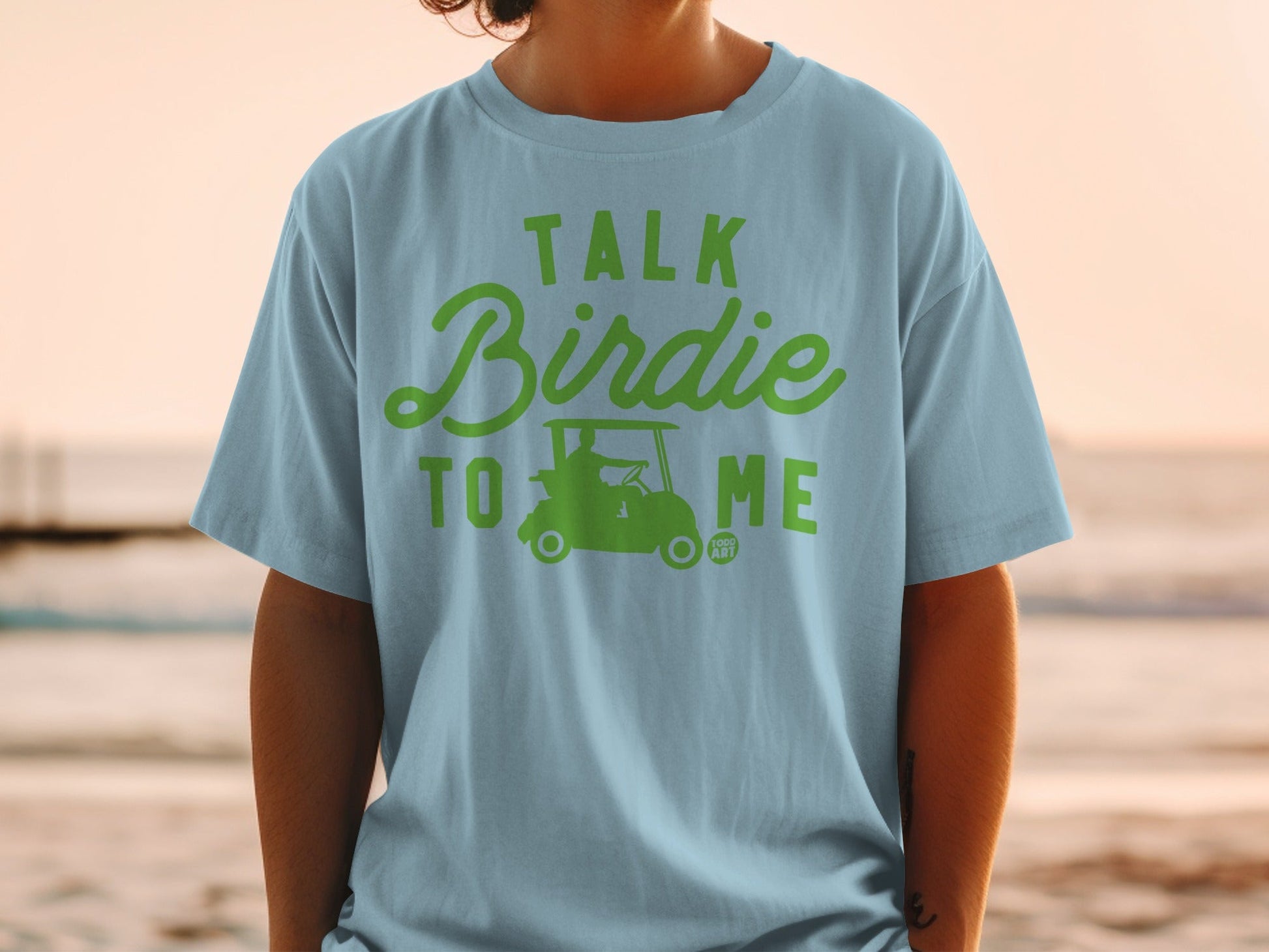 Light blue t-shirt with green text "TALK BIRDIE TO ME" and golf cart graphic.