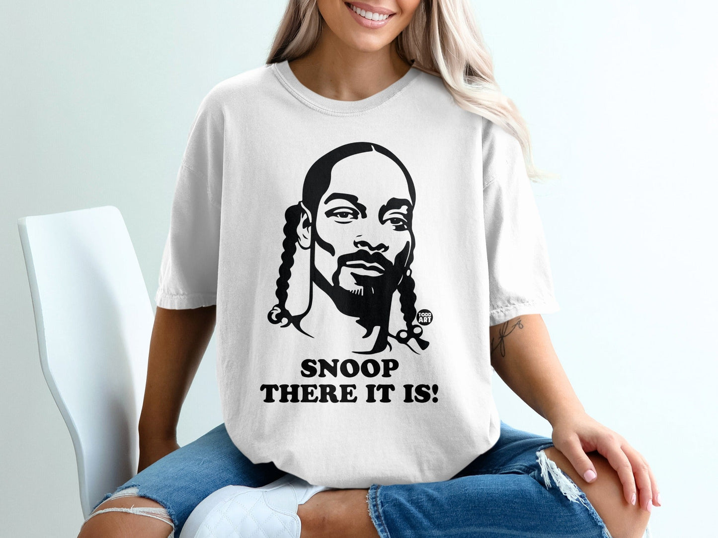 White t-shirt with black graphic of Snoop Dogg and text "SNOOP THERE IT IS!".