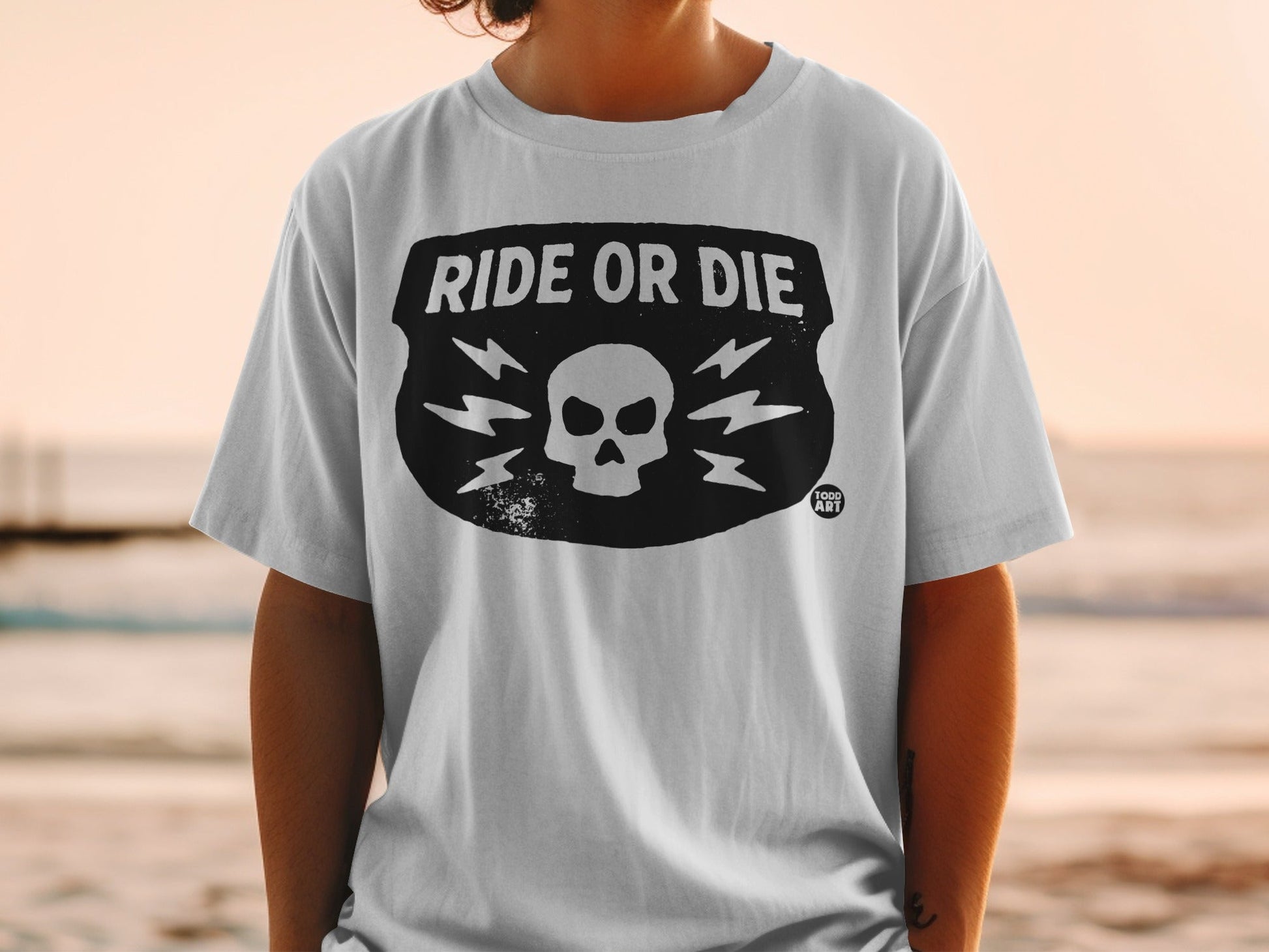 White t-shirt with "Ride or Die" skull and lightning bolt graphic.