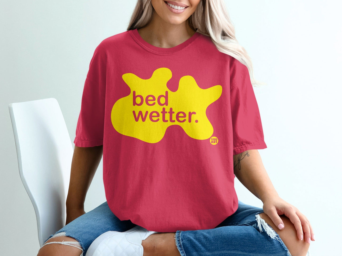 Pink t-shirt with yellow blob design and text "bed wetter.".