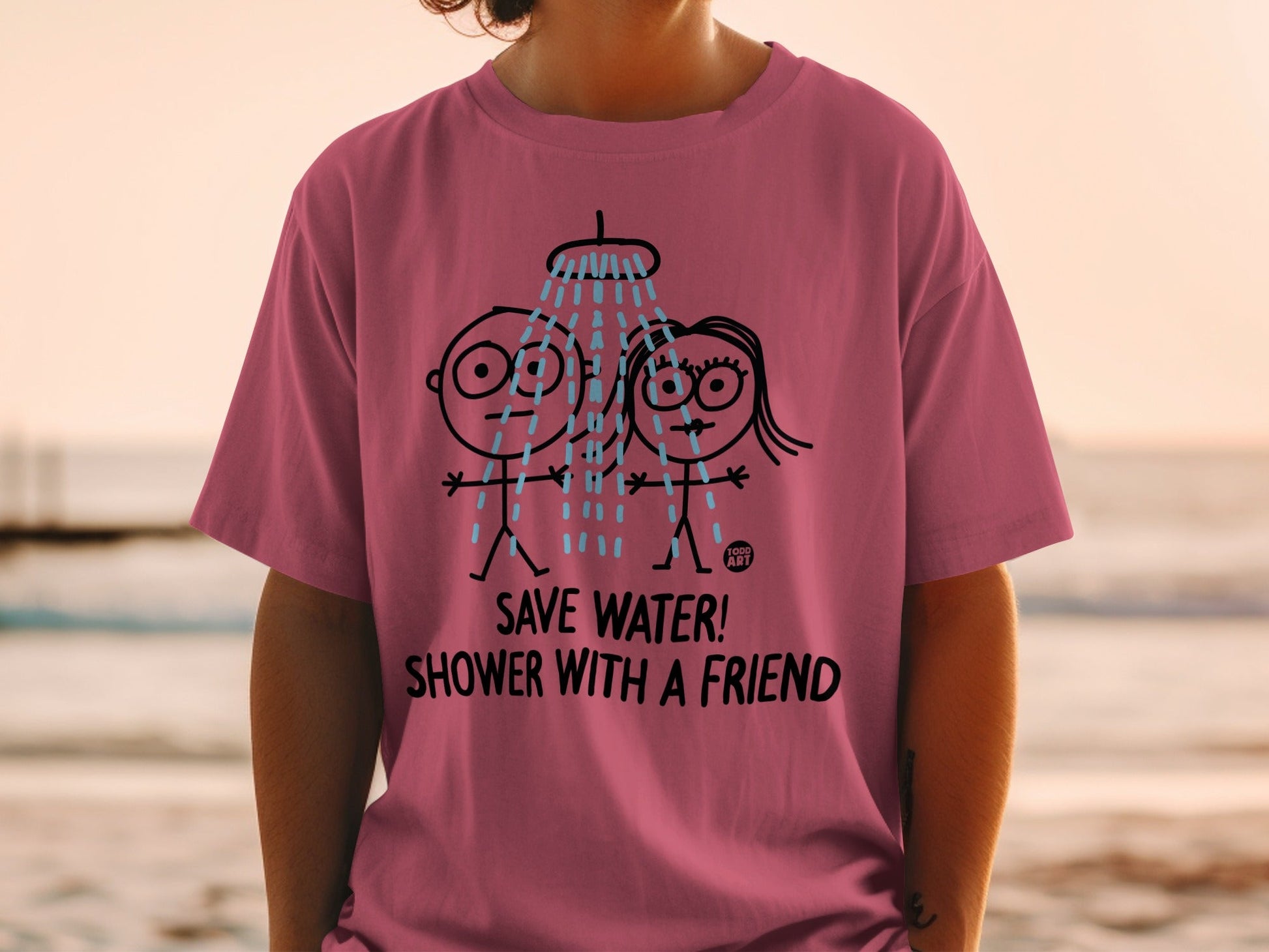 Pink t-shirt with cartoon figures showering and text "SAVE WATER! SHOWER WITH A FRIEND."