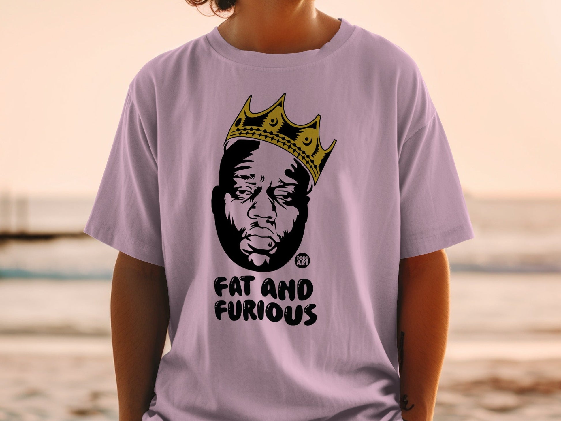 Lilac t-shirt with crown and portrait of a man, "Fat and Furious" text.