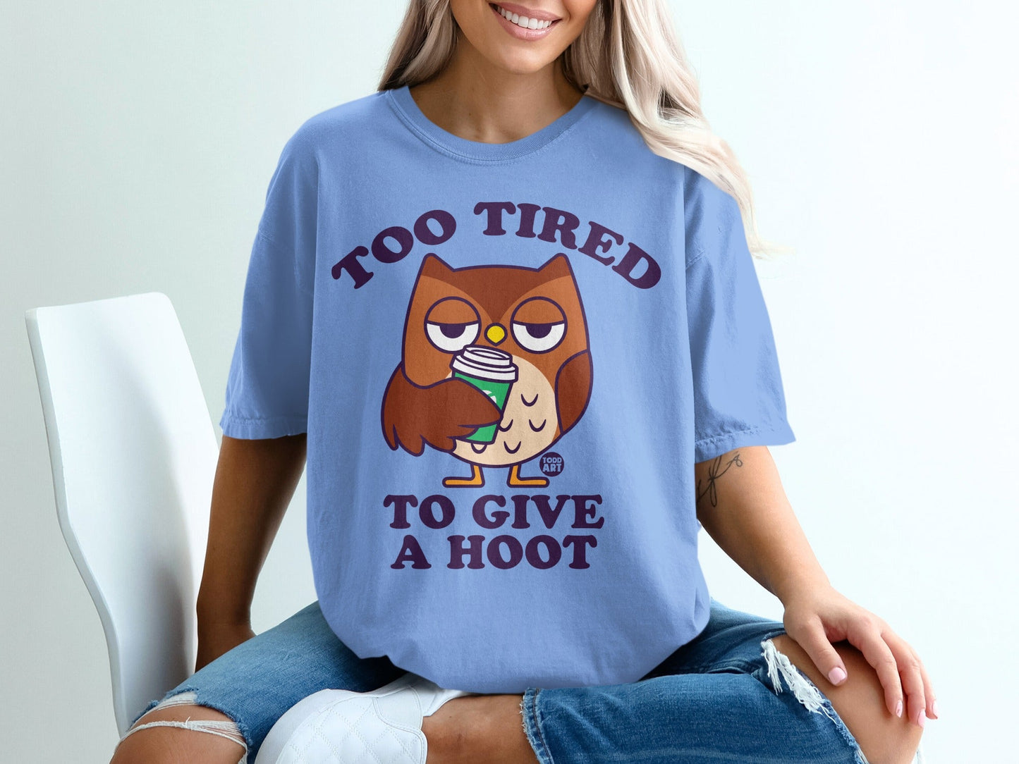 Blue t-shirt with cartoon owl holding coffee, text reads "TOO TIRED TO GIVE A HOOT".