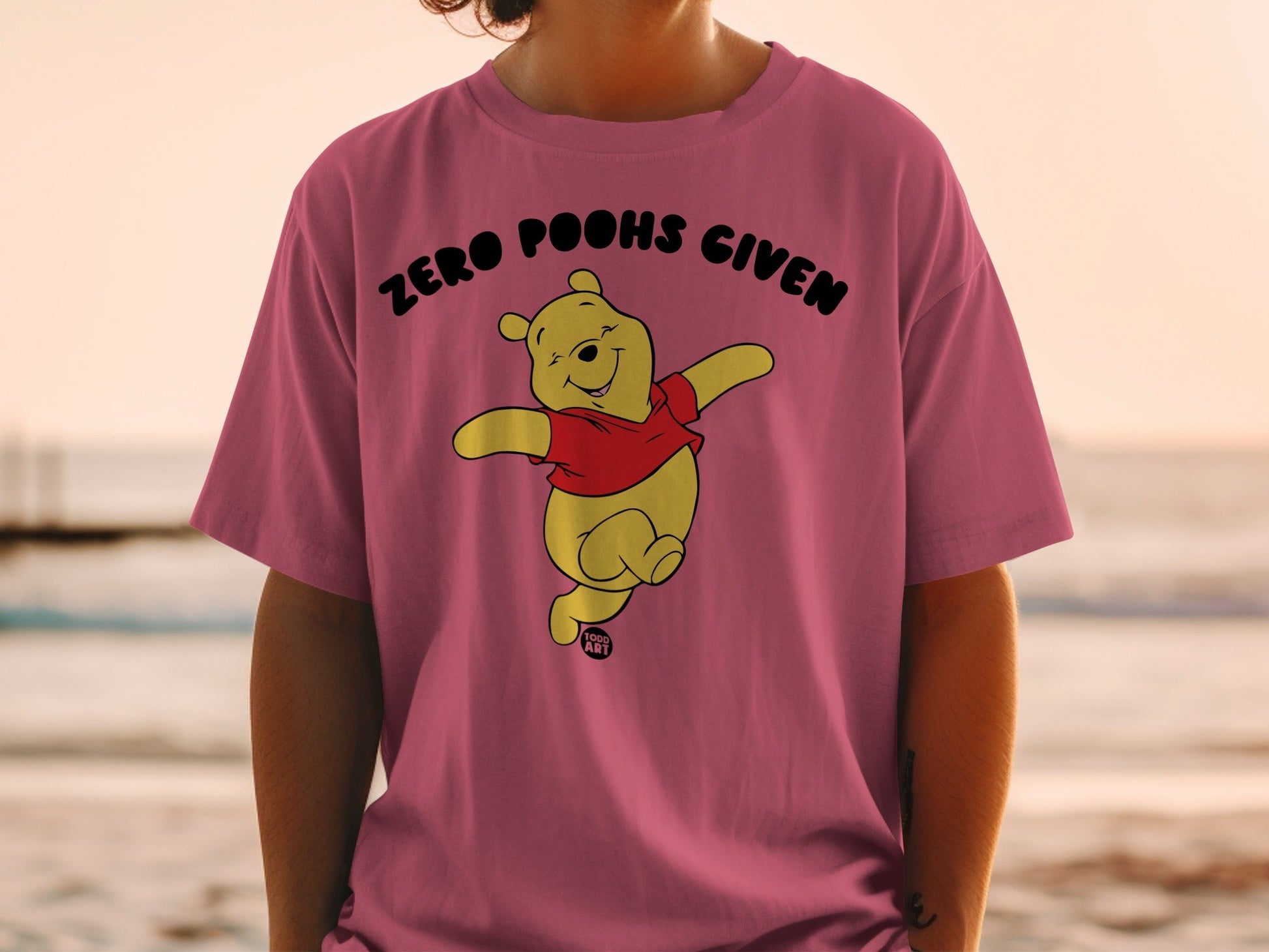 Winnie the Pooh on a pink t-shirt with "Zero Poohs Given" text.