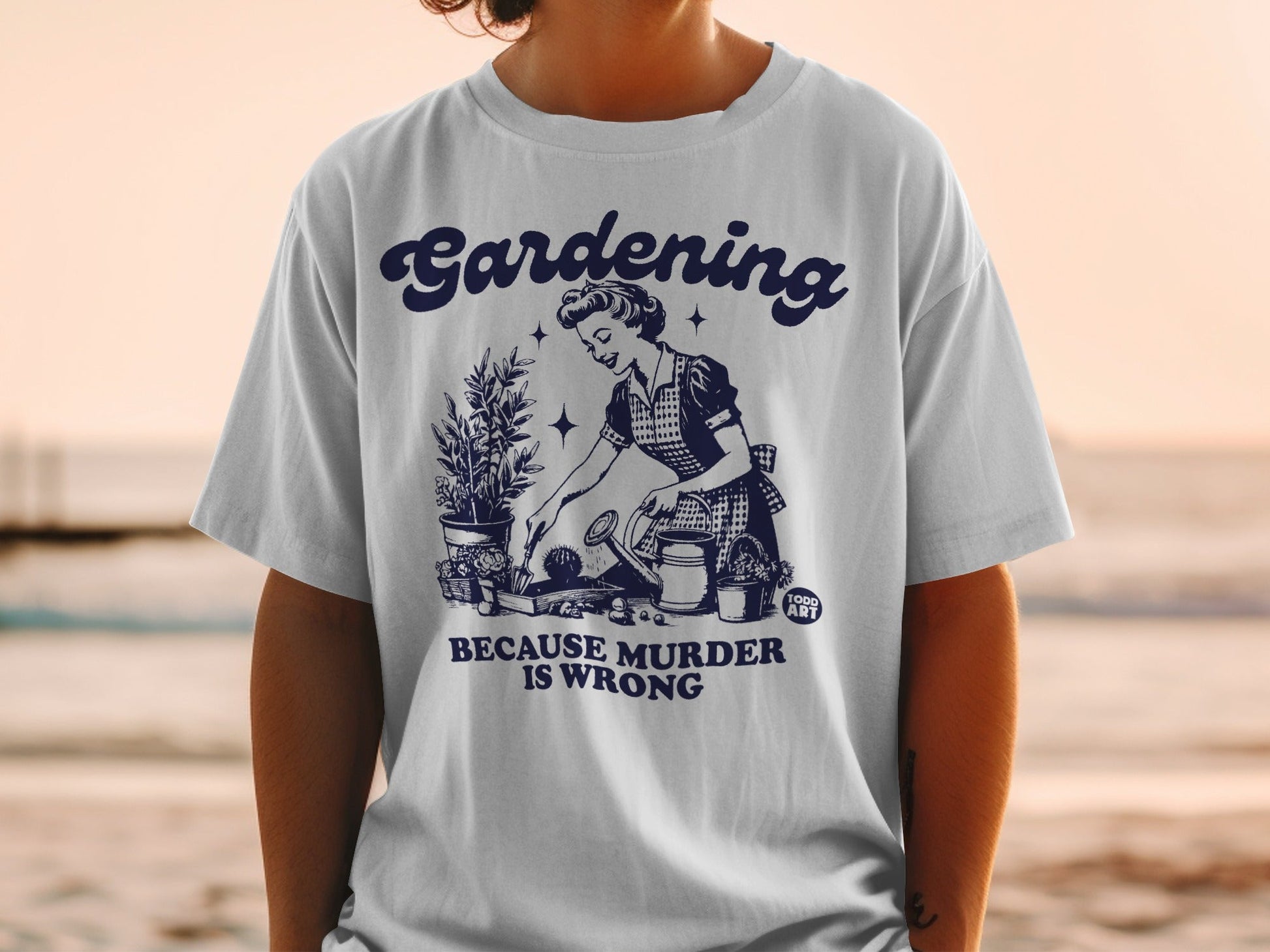 White t-shirt with "Gardening Because Murder is Wrong" text and retro gardening illustration.