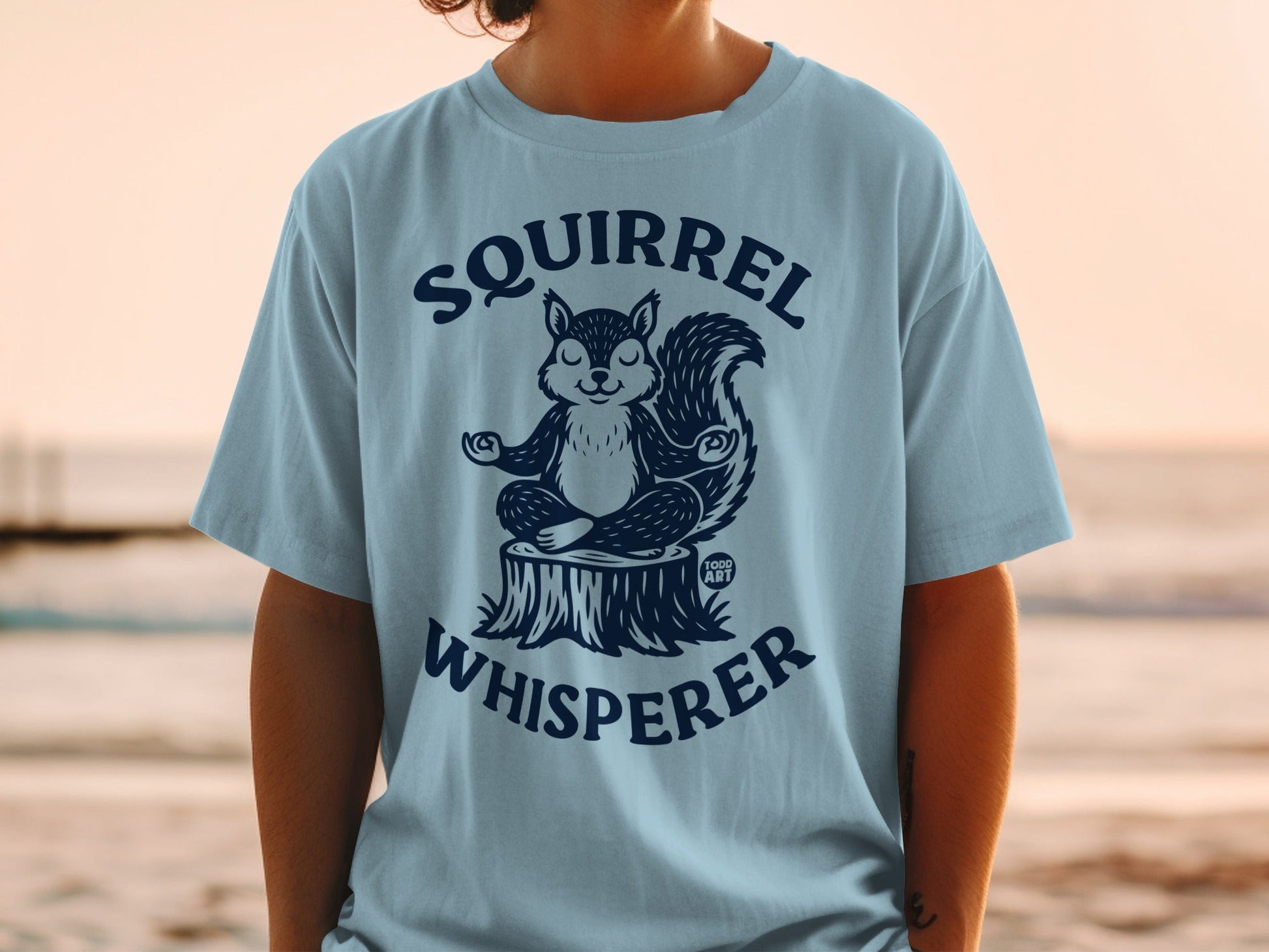 Light blue t-shirt with a meditating squirrel and "Squirrel Whisperer" text.