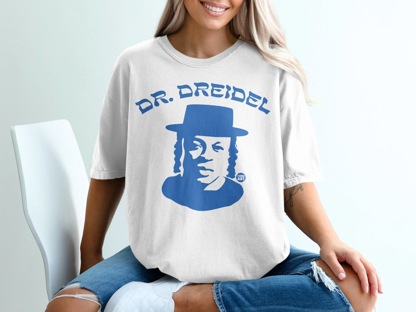 White t-shirt with blue graphic of "DR. DREIDEL" and a man's portrait.